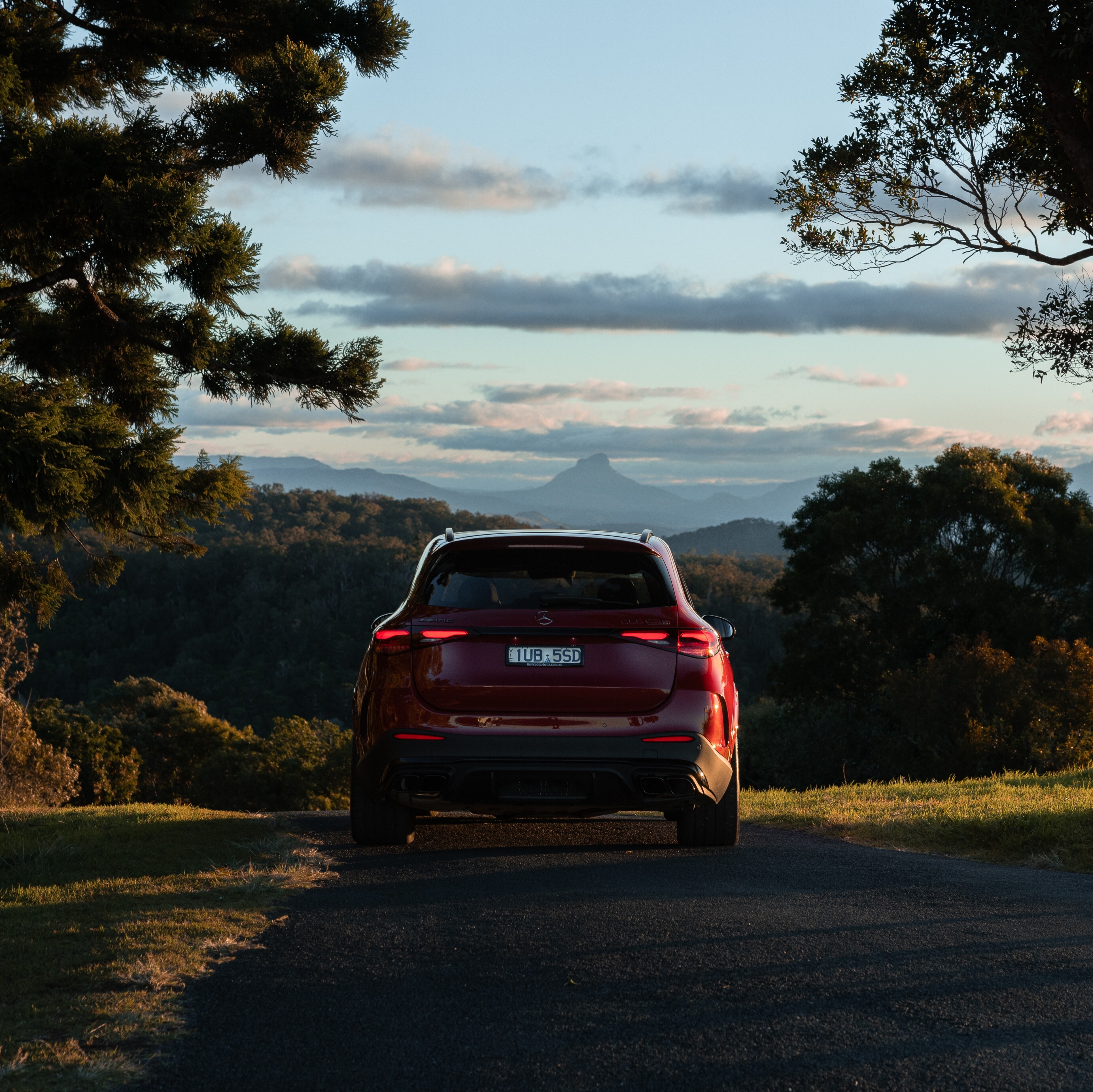 A red Mercedes-AMG GLC 63 S E PERFORMANCE driving down a country road.