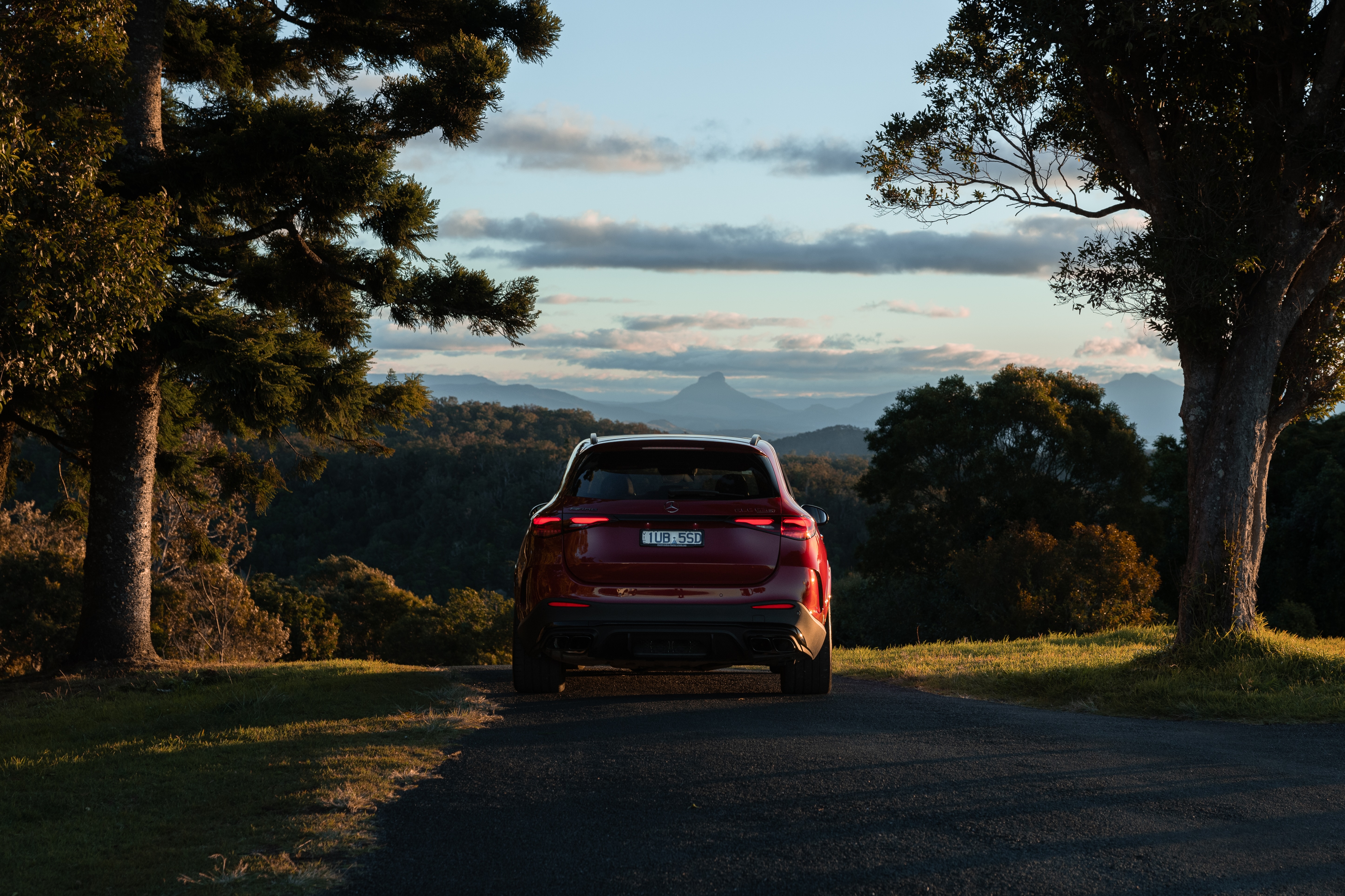 A red Mercedes-AMG GLC 63 S E PERFORMANCE driving down a country road. A red Mercedes-AMG GLC 63 S E PERFORMANCE driving down a country road.