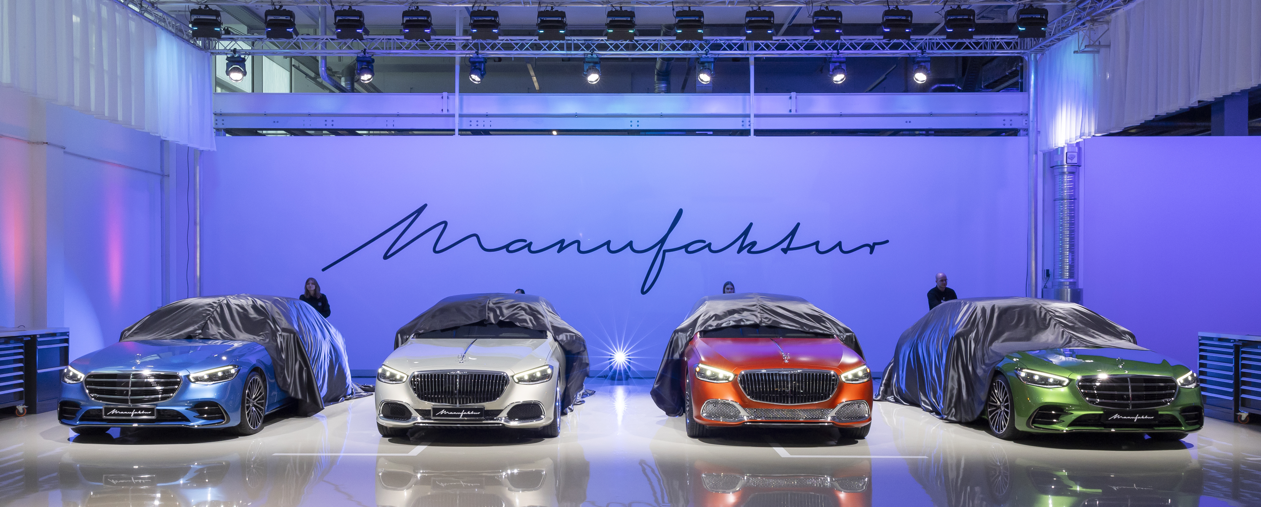 A line of four cars being unveiled at the Mercedes-Benz MANUFAKTUR Studio Mercedes-Benz MANUFAKTUR Studio