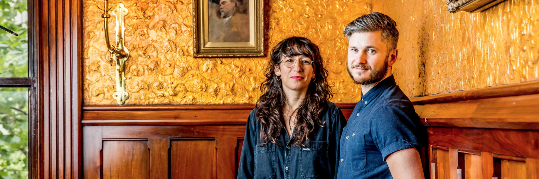 Georgia Nowak and Eugene Perepletchikov Georgia Nowak and Eugene Perepletchikov standing in front of a gold wall