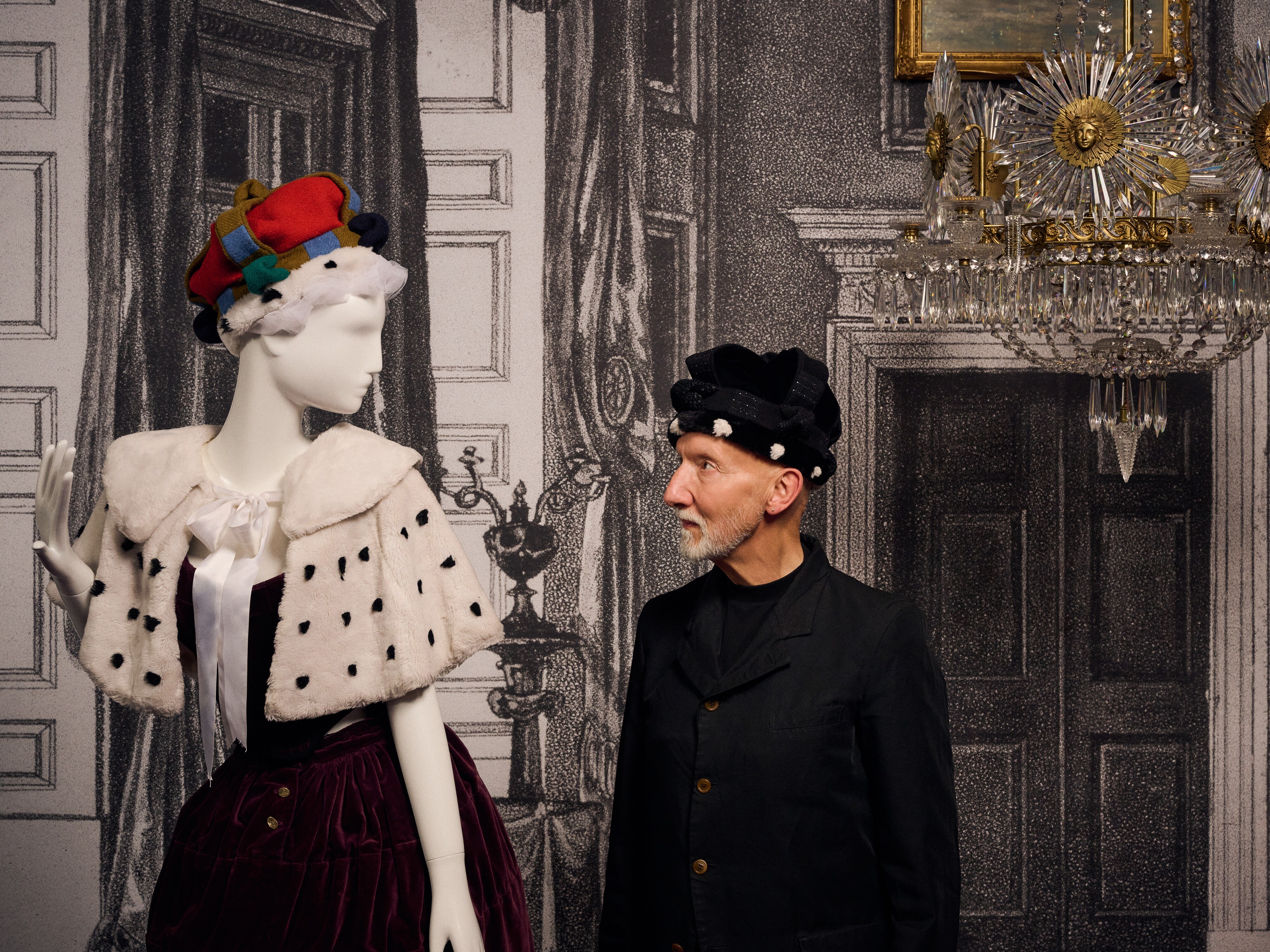 A bearded man in a hat, milliner Stephen Jones, looks at one of his designs for Vivienne Westwood.