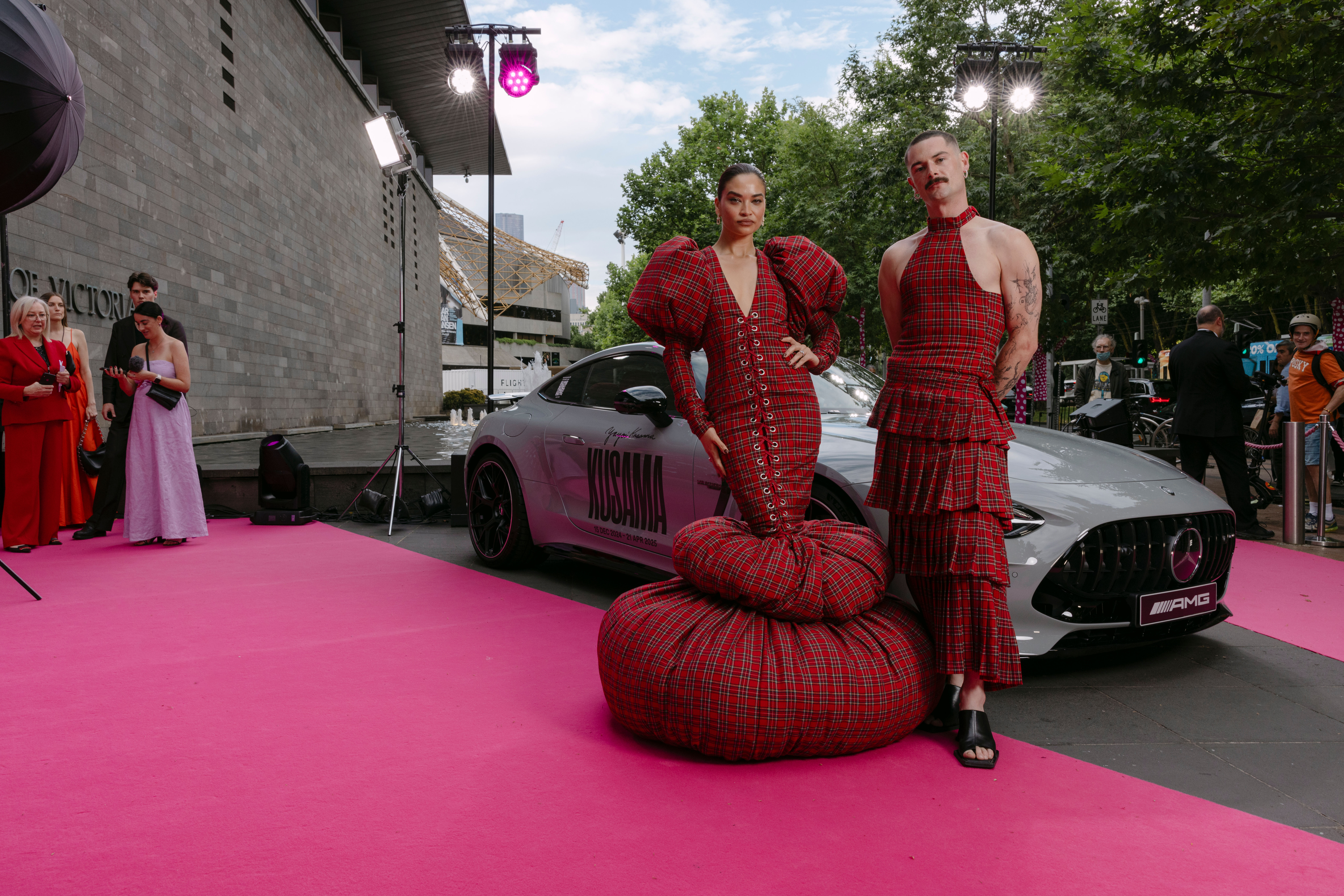 Model Shanina Sheik and fashion designer Jarrod Reid posing in tartan next an alpine grey Mercedes-AMG GT Coupe on the pink carpet outside the NGV Model Shanina Sheik and fashion designer Jarrod Reid posing in tartan next an alpine grey Mercedes-AMG GT Coupe on the pink carpet outside the NGV
