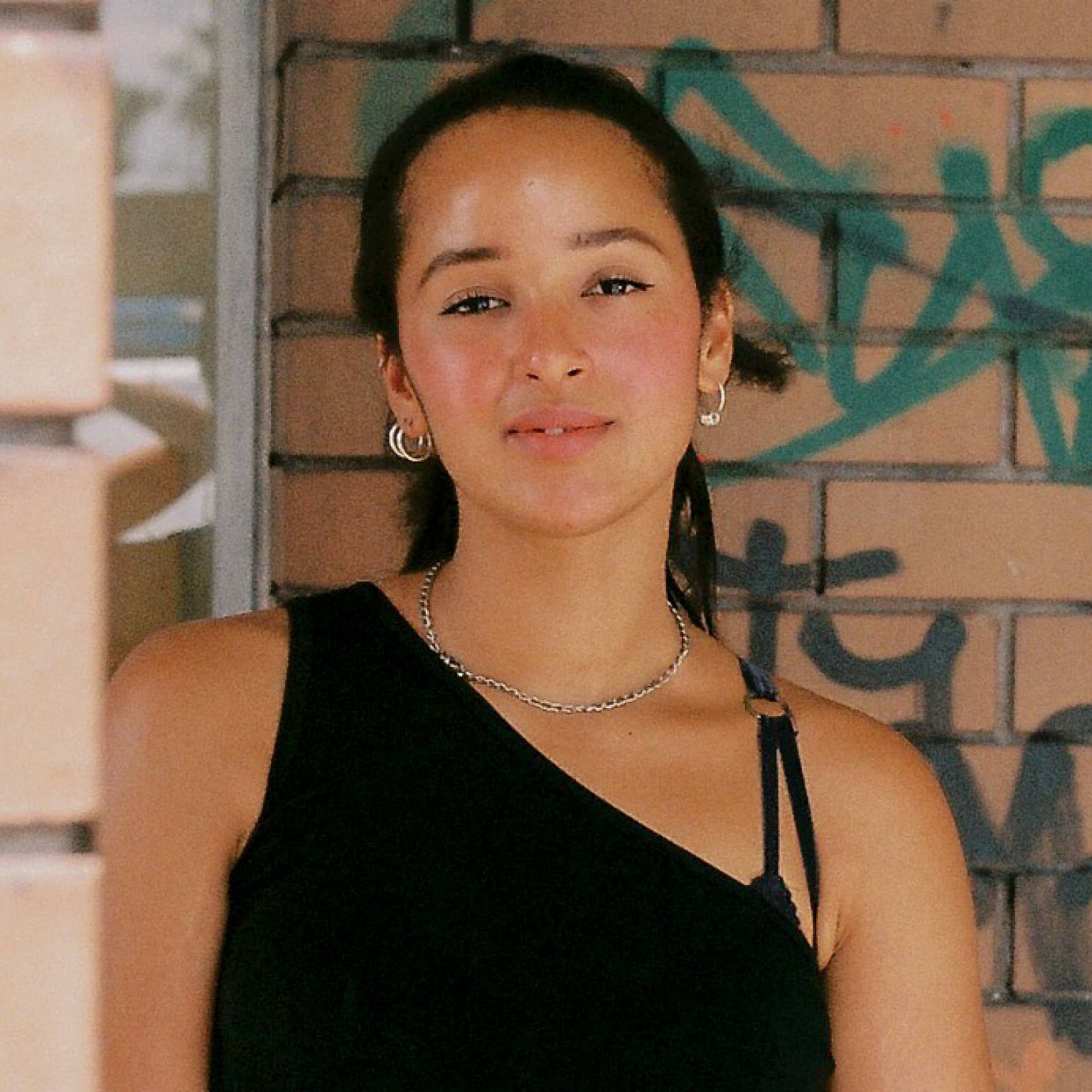 Sabina McKenna stands in front of a brick wall with her hands held in front of her