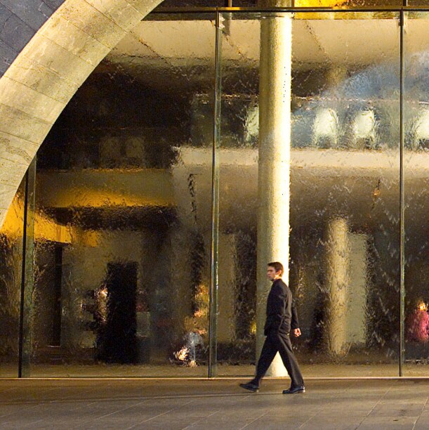 A man walking in front of a large glass waterwall