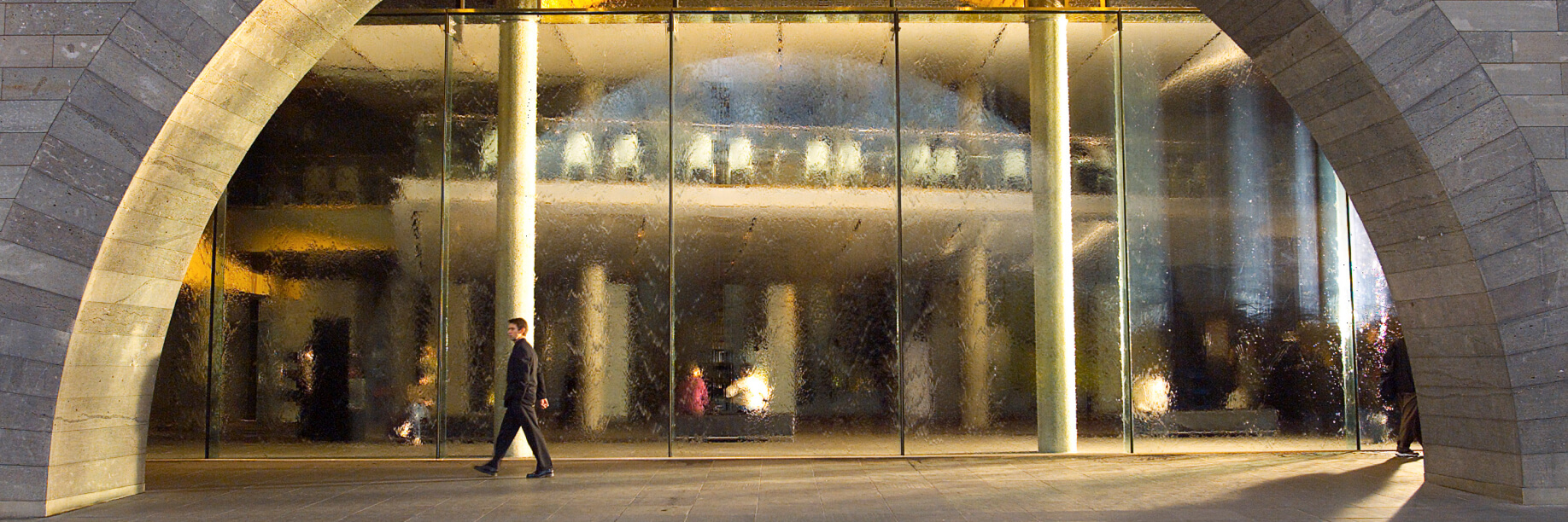The Waterwall at NGV A man walking in front of a large glass waterwall