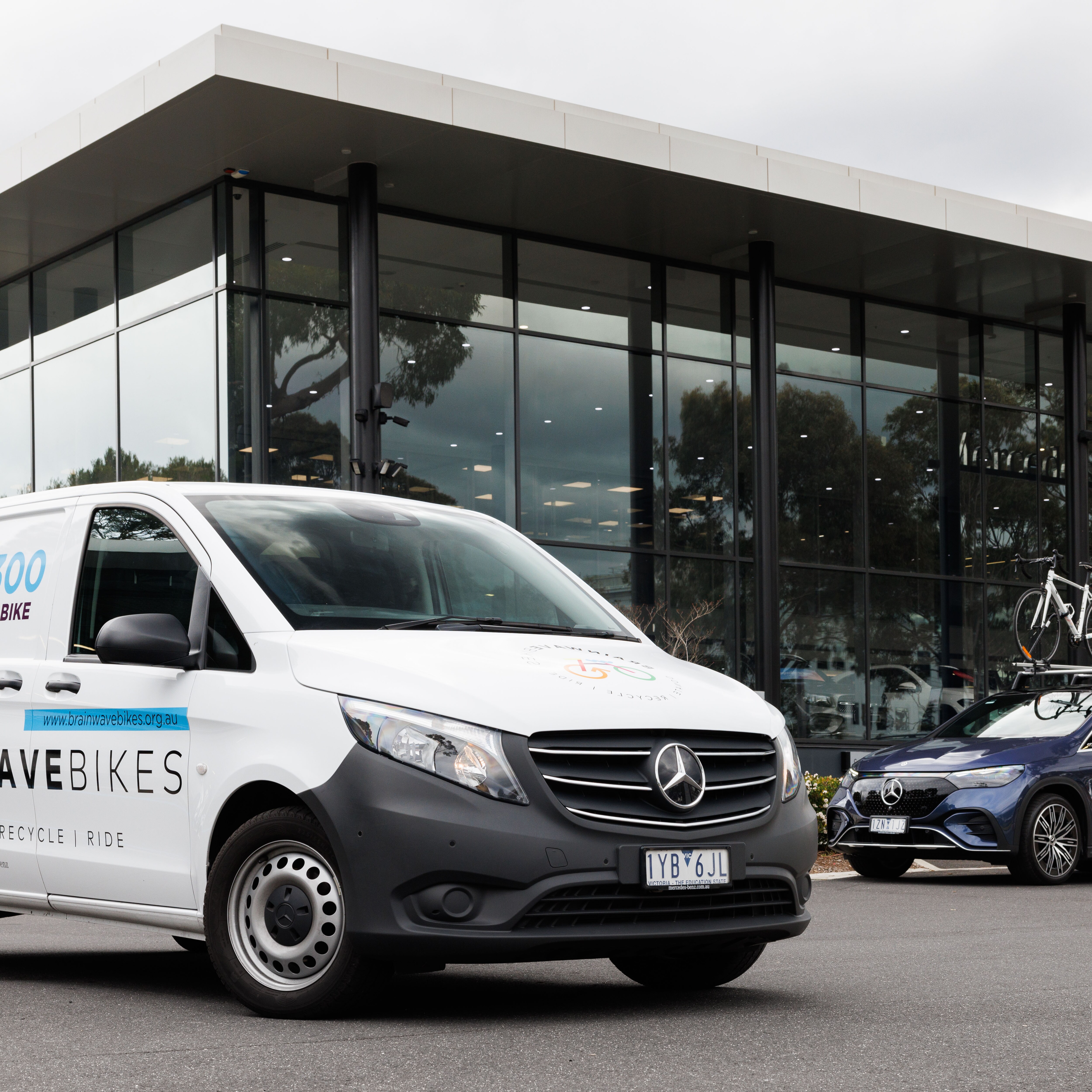 A Mercedes-Benz van and car parked outside a retailer.