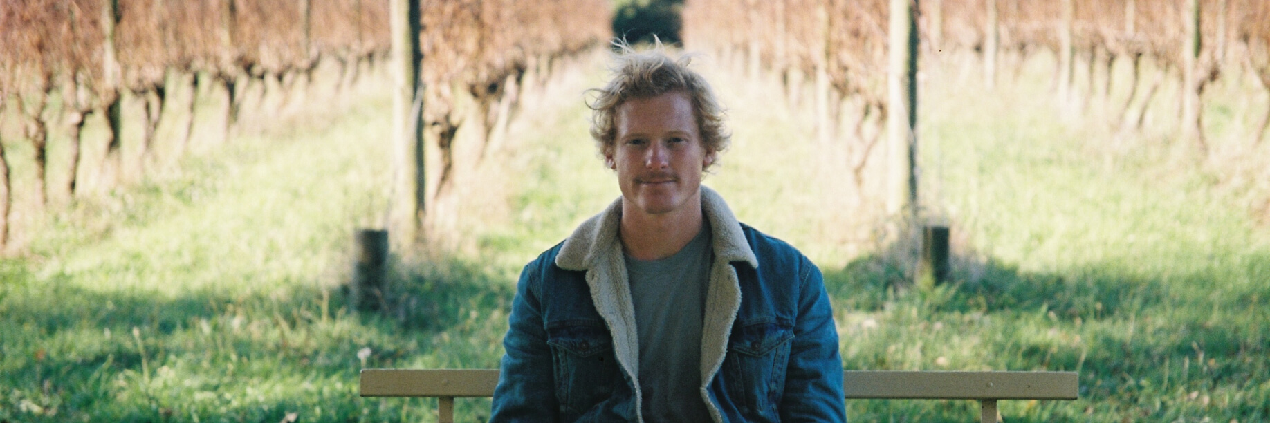 Jordy Kay in front of his vineyard A man sits on a bench in a vineyard
