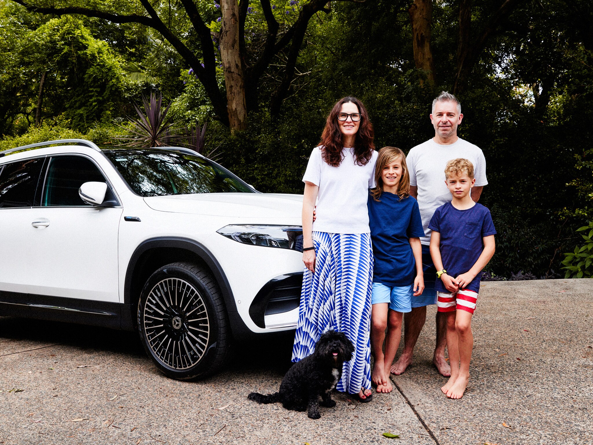 The Robinson family standing together in their driveway next to a white all-electric EQA. Image credit/photographer: Alisha Gore