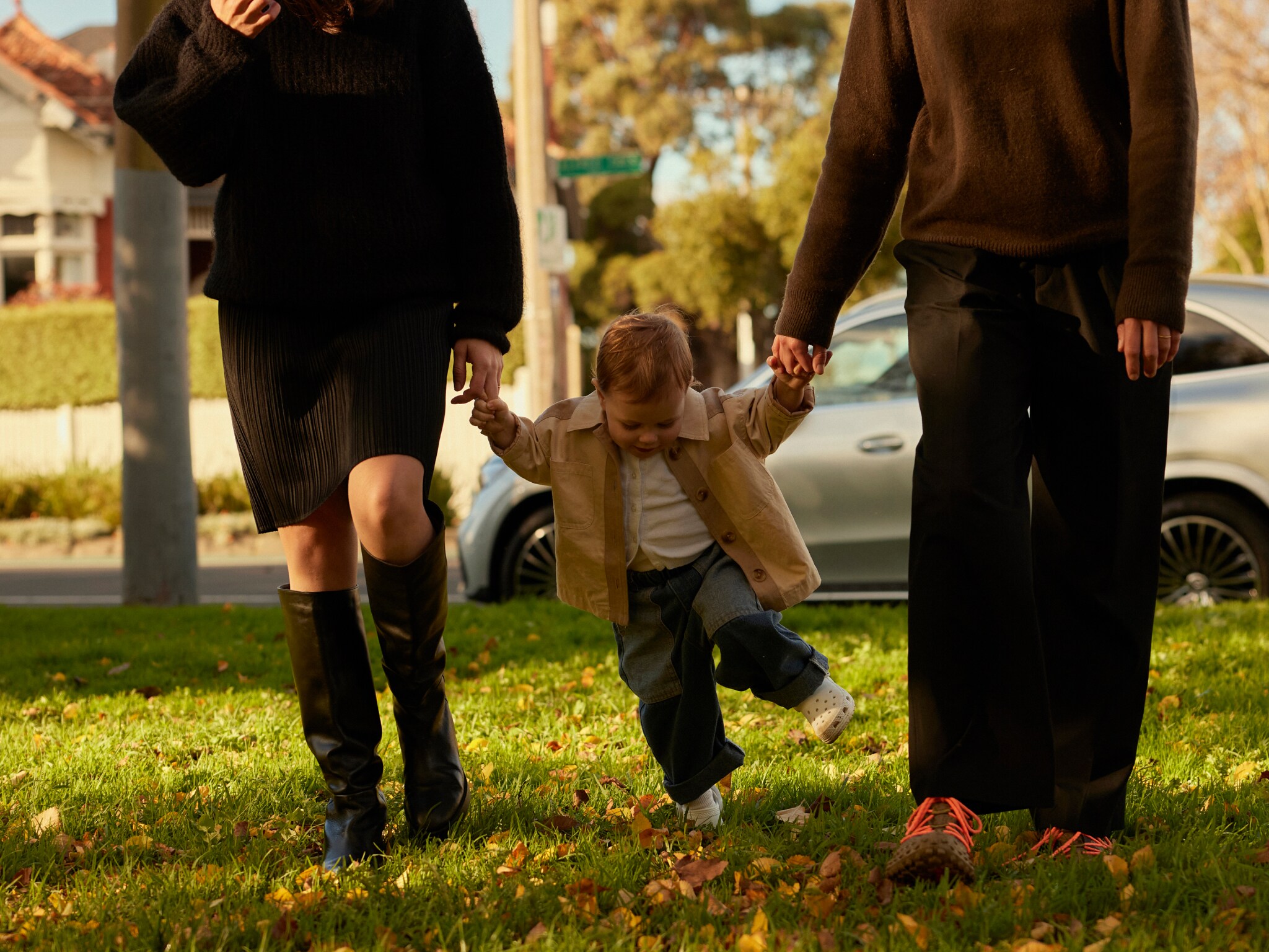 A toddler holding onto her parents’ hands. Image credit/photographer: Sean Fennessy