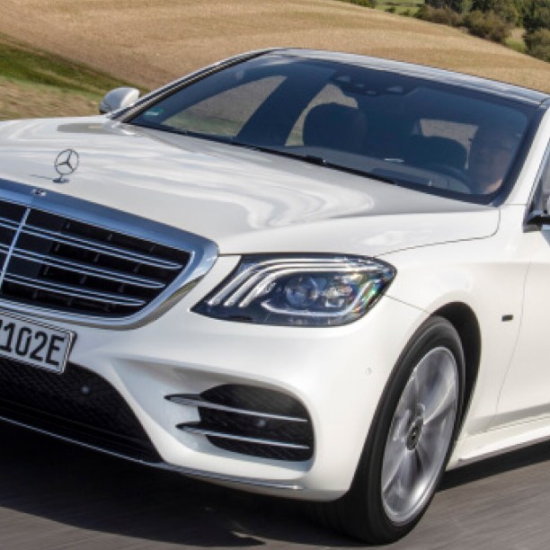 A white car drives on a road