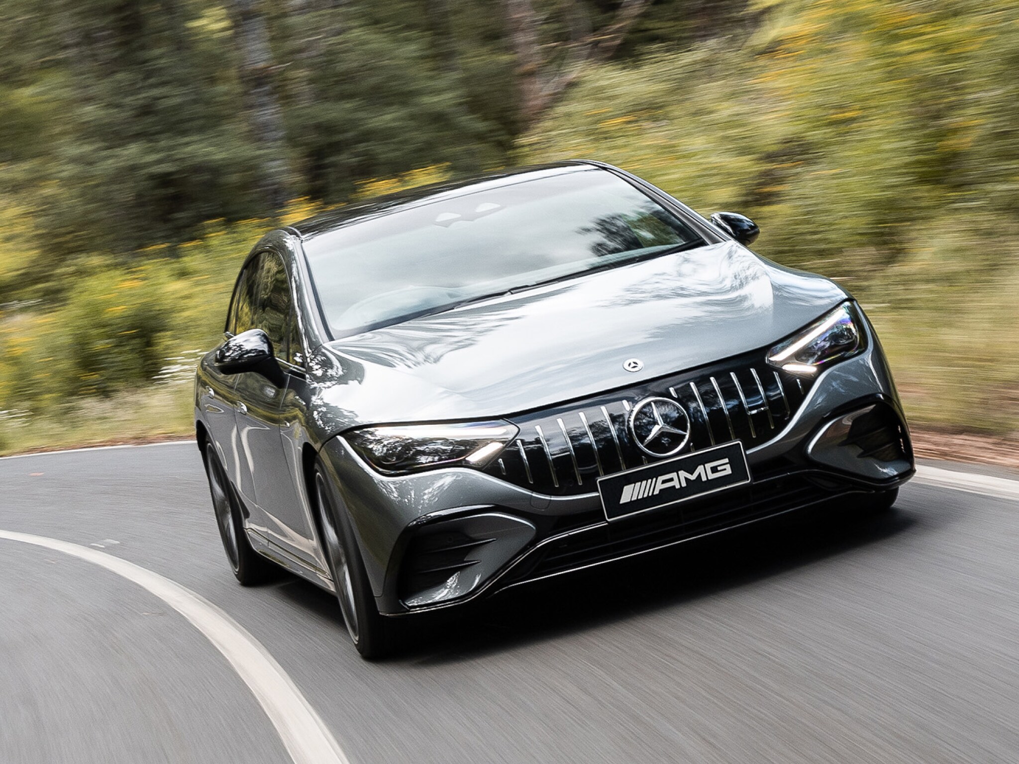 A grey all-electric Mercedes-AMG EQE 53 driving down a winding country road. Image credit/photographer: Nathan Jacobs