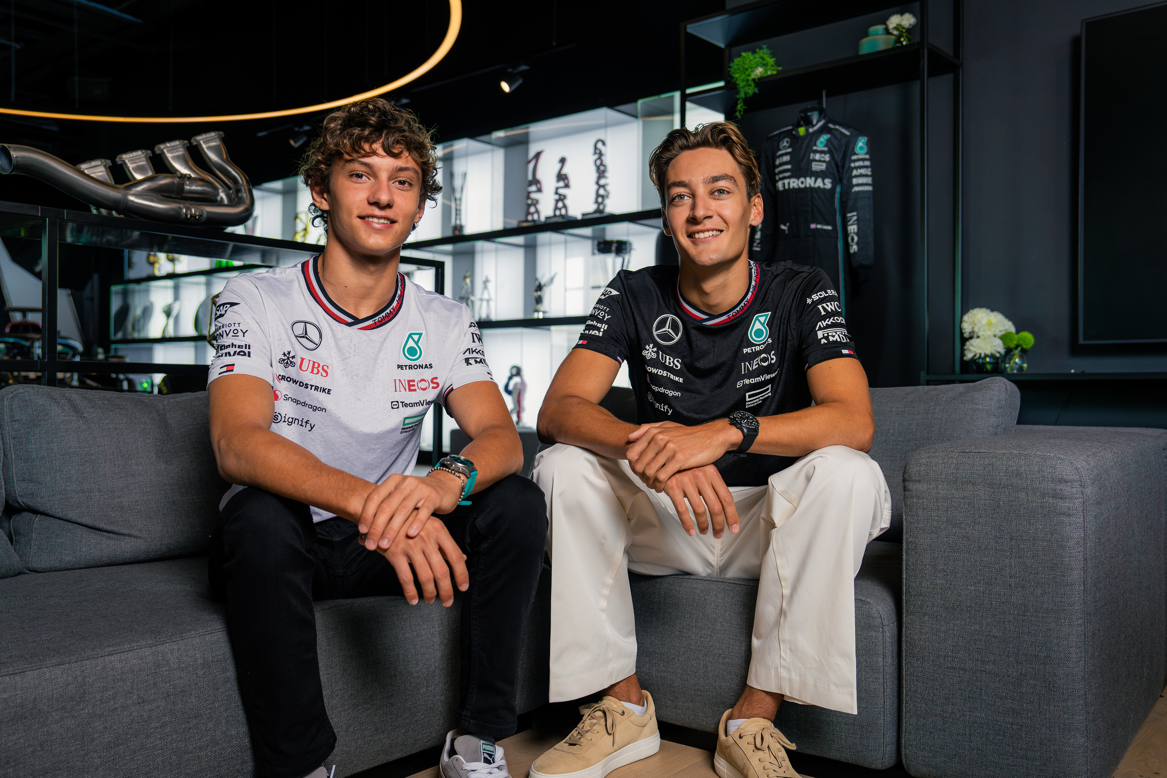 Andrea Kimi Antonelli and George Russell Andrea Kimi Antonelli and George Russell sitting on a couch and smiling.