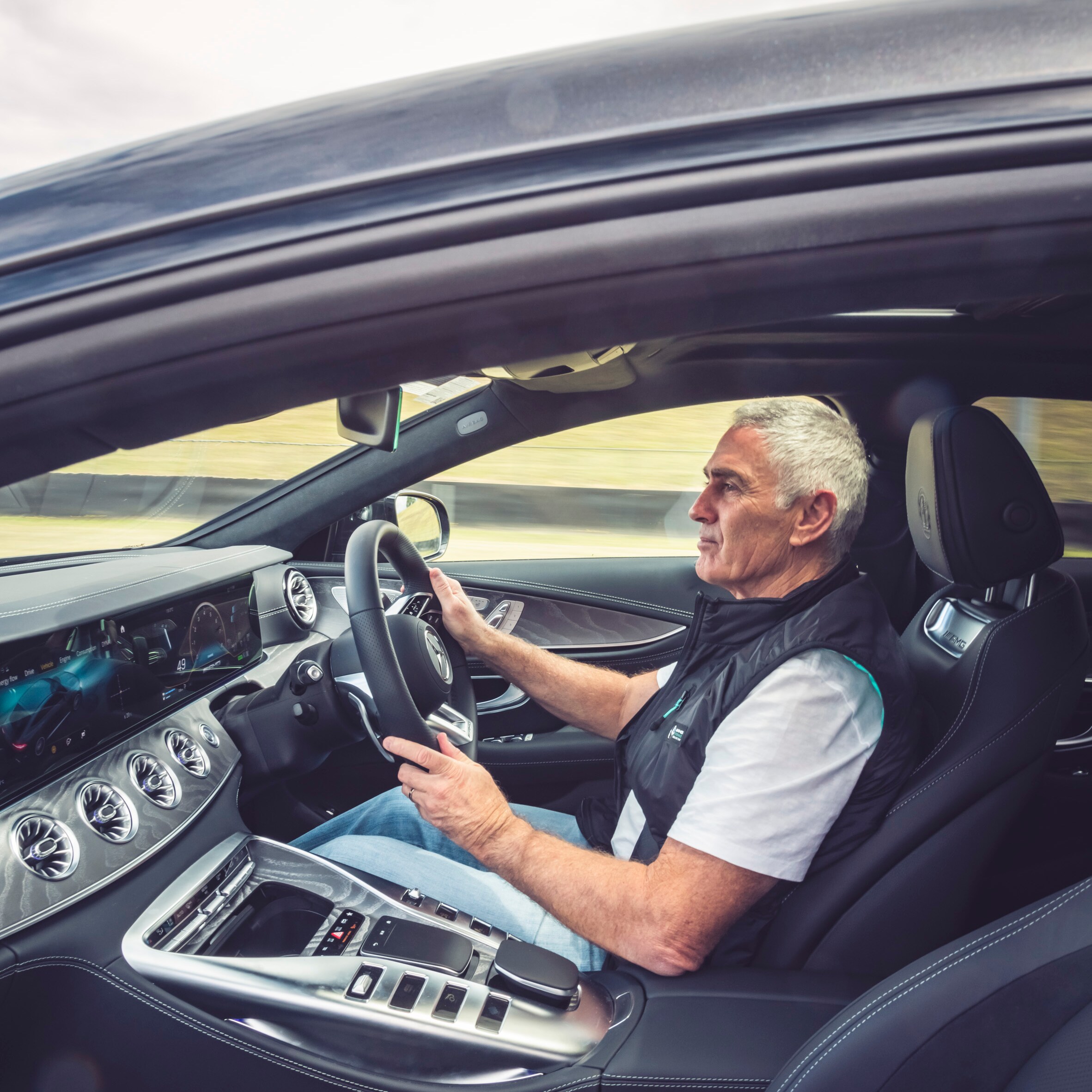 Mick Doohan standing next to a Mercedes-AMG GT 63 S E PERFORMANCE at Sydney Motorsport Park. 