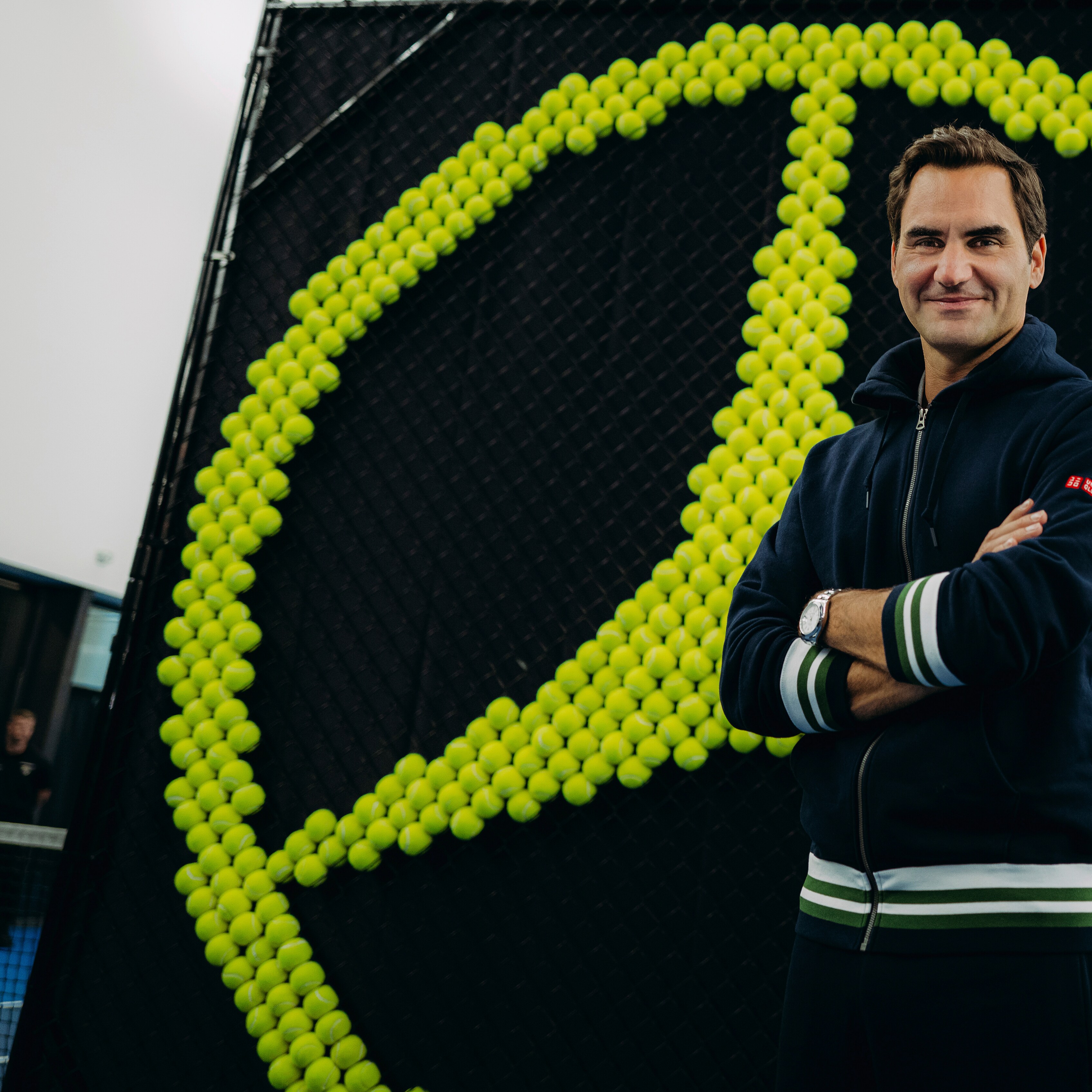 Roger Federer taking a selfie with two Mercedes-Benz cars at the back