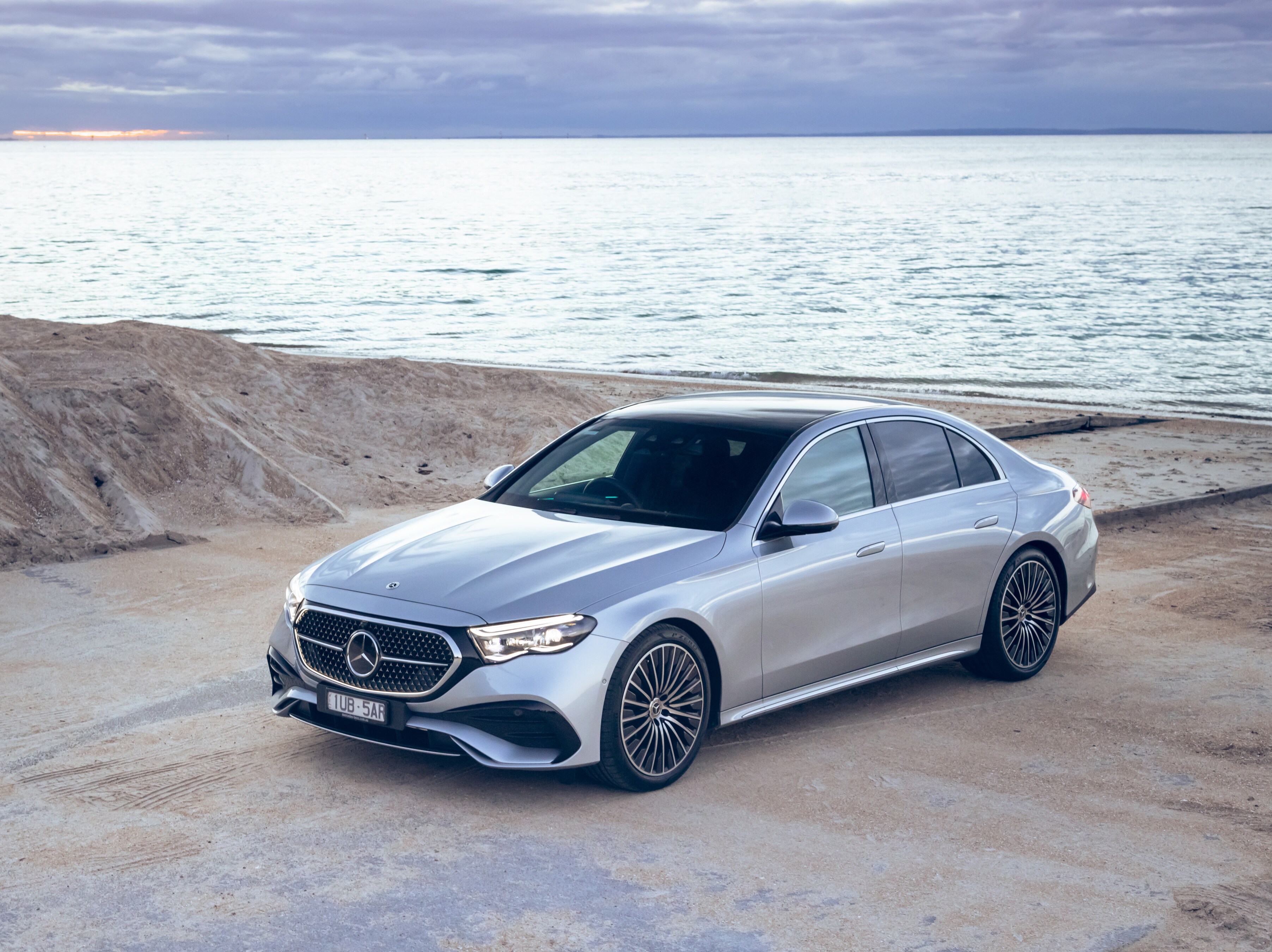 A silver Mercedes-Benz E-Class parked by a beach