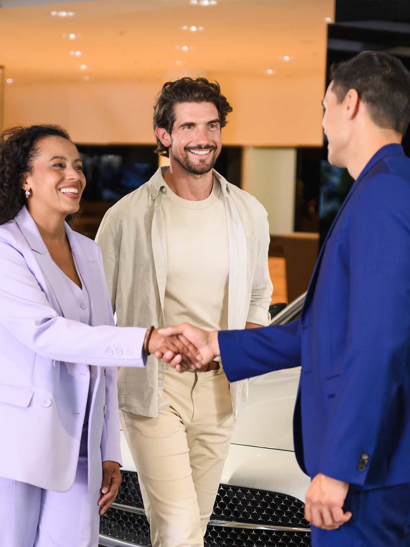 A couple speaking to a business manager in a dealership.