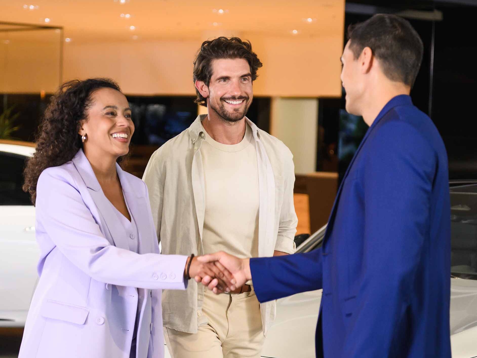 A couple speaking to a business manager in a dealership.