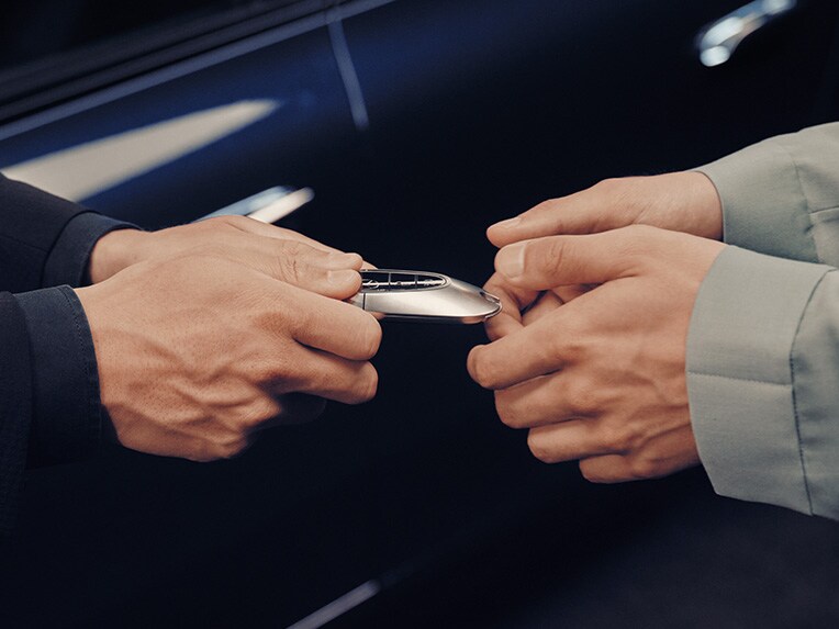 A person handing over a car key to another person