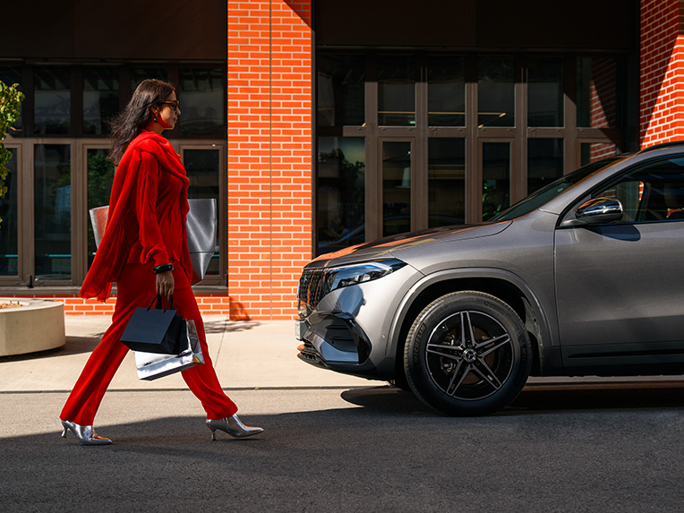 A woman walking towards a Mercedes-Benz vehicle. A woman walking towards a Mercedes-Benz vehicle.