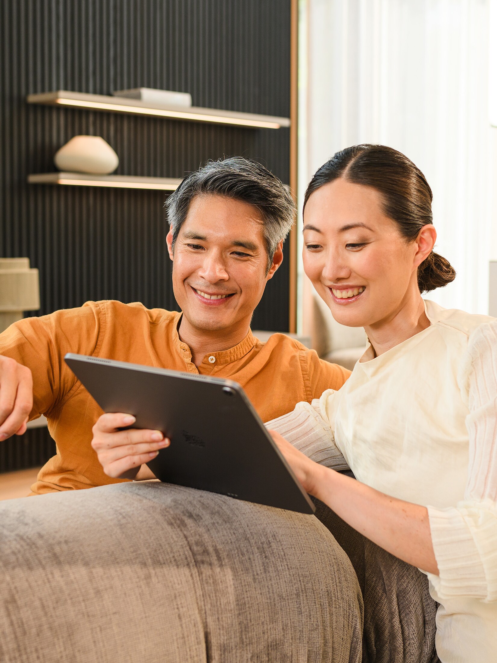 Two people on a sofa looking at a mobile device.