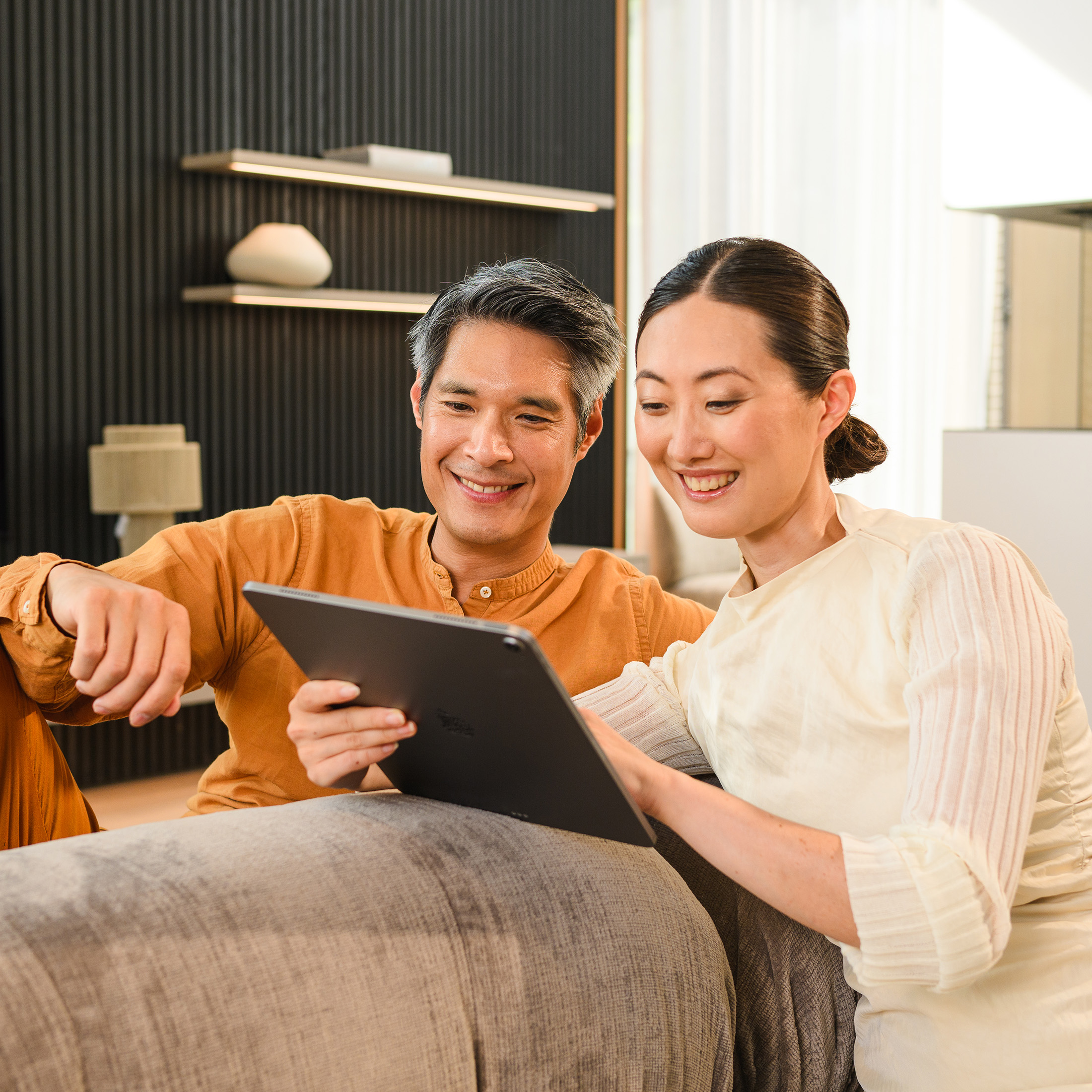 Mercedes-Benz Finance Calculator. Two people on a sofa looking at a mobile device.