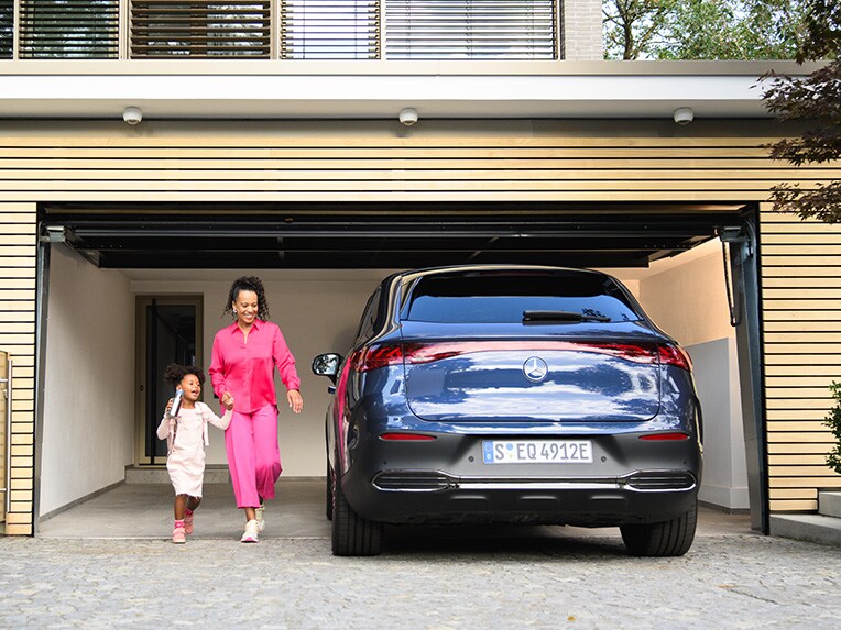 A person and child walking to a Mercedes-Benz vehicle. 