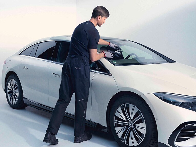 A person fixing the windscreen of a Mercedes-Benz vehicle. 