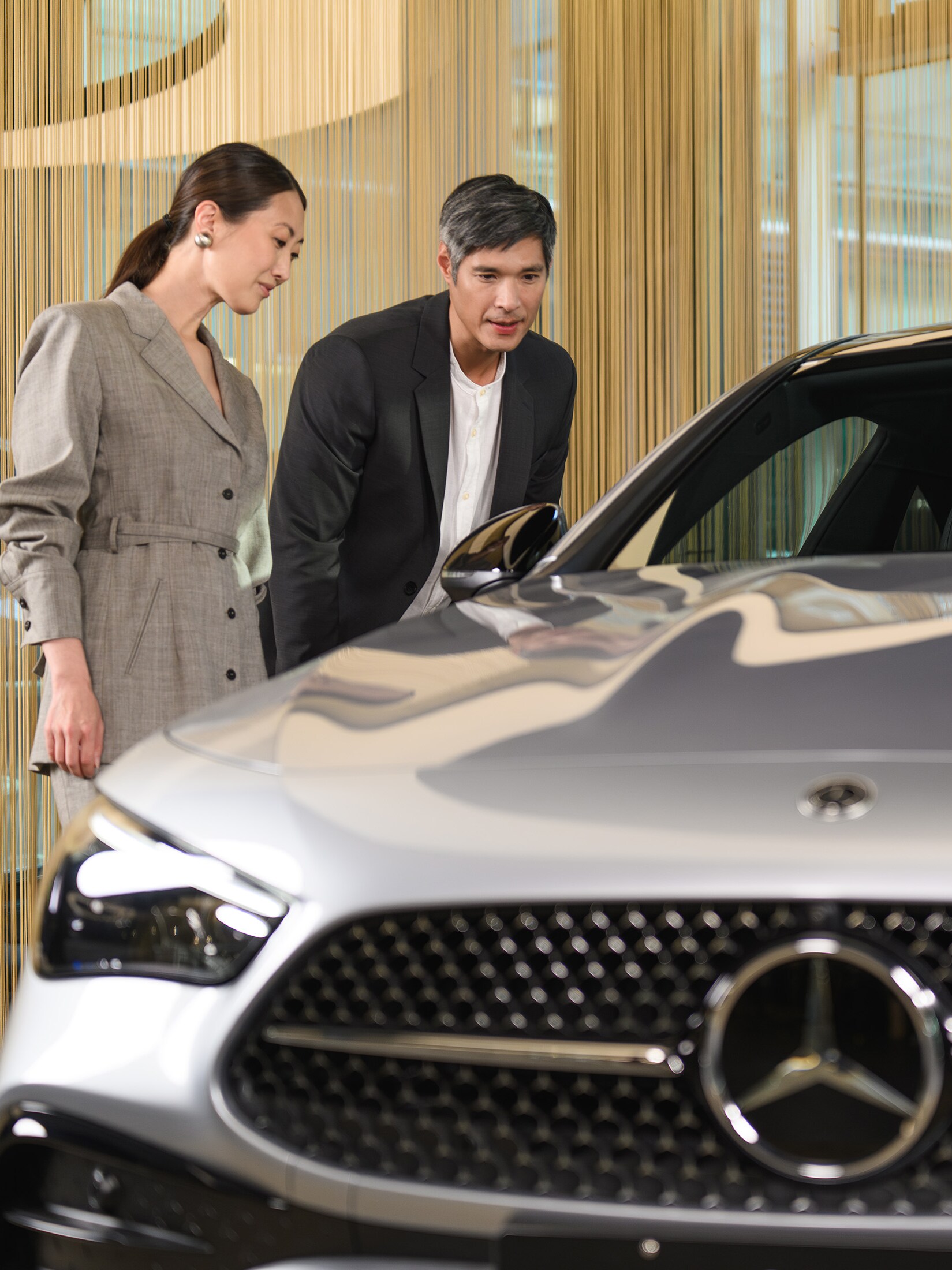 Man and woman looking at a Mercedes-Benz car