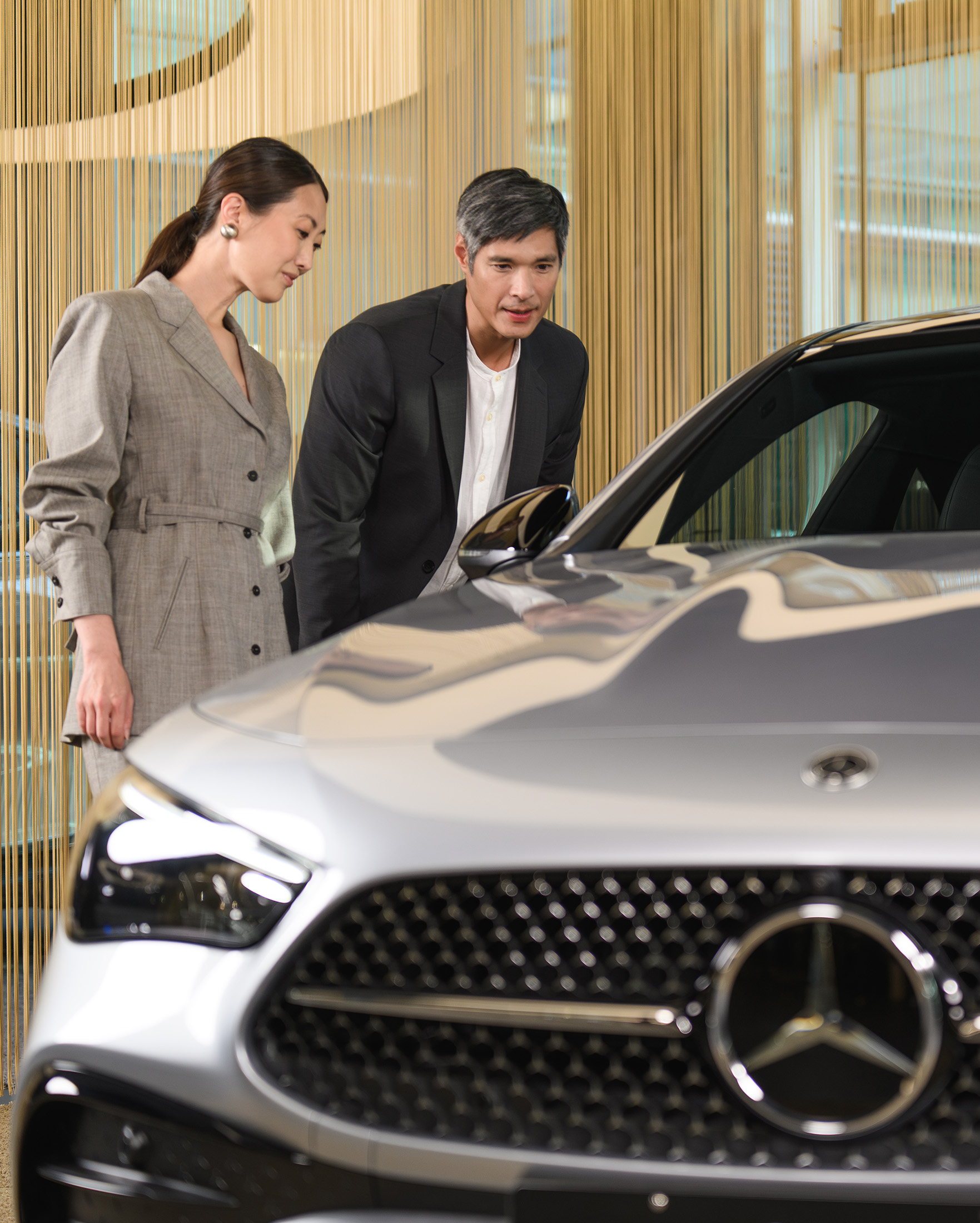 Man and woman looking at a Mercedes-Benz car Man and woman looking at a Mercedes-Benz car