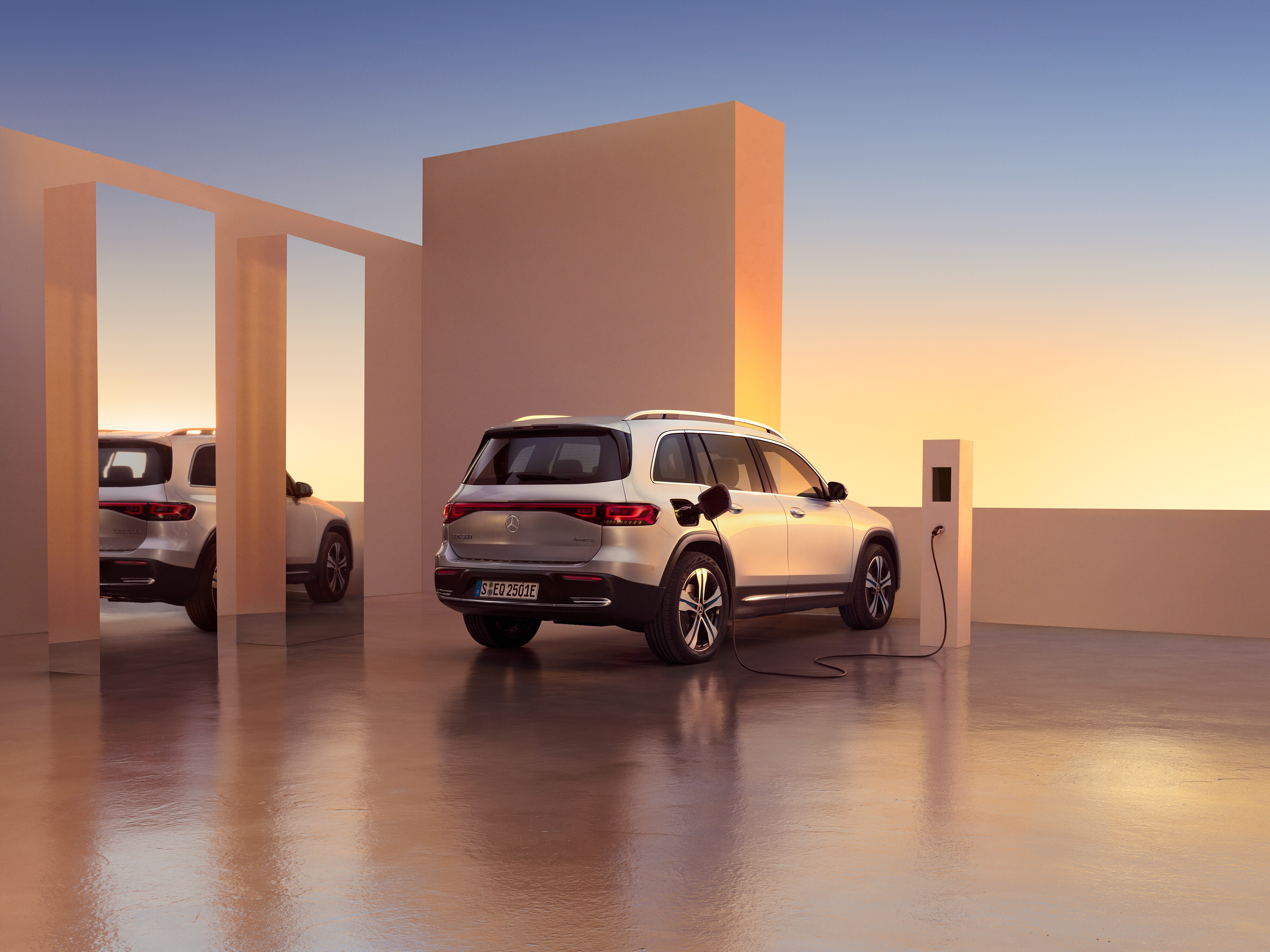 A man and a woman conveniently charge their Mercedes-Benz at a charging station using Charging Digital Extras .