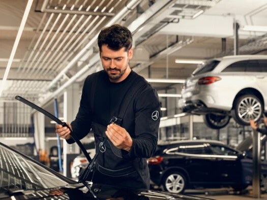 Technician fitting windscreen wiper blade in a workshop