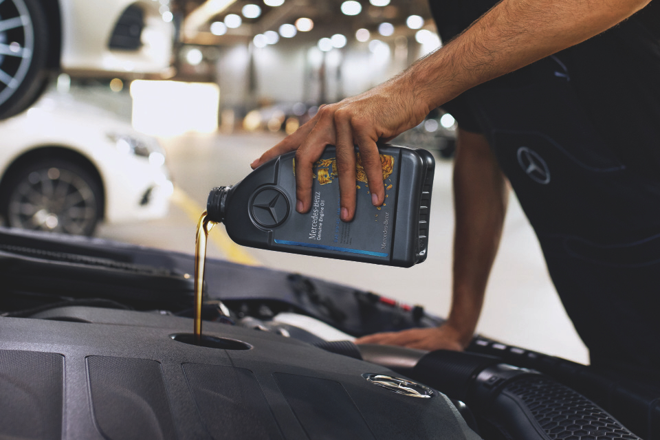 Mercedes-Benz Genuine Engine Oil Close‑up of engine bay with Mercedes‑Benz genuine engine oil being poured.