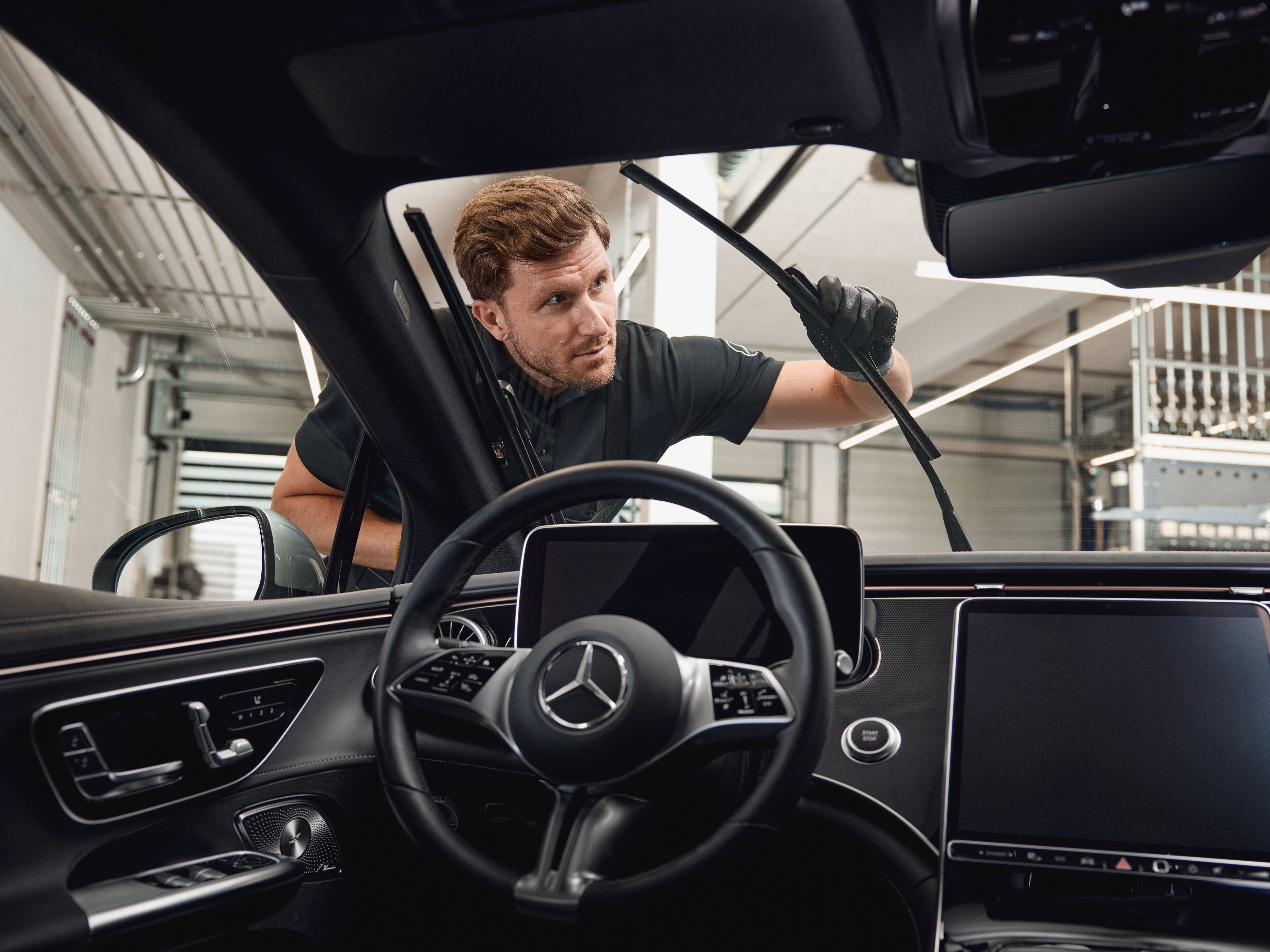 Interior view of a Mercedes‑Benz vehicle with a technician exchanging genuine wiper blades.
