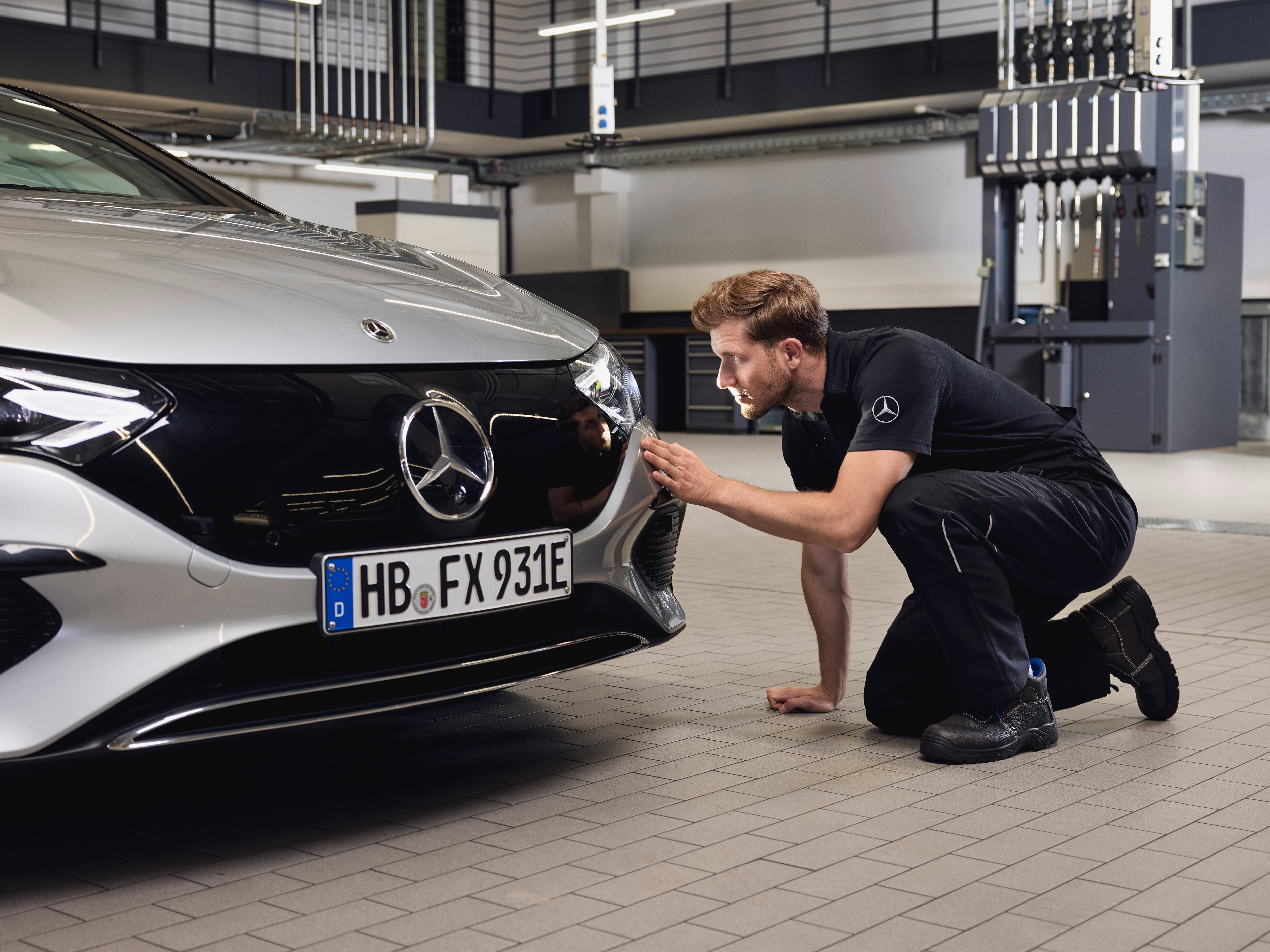 Close‑up of a Mercedes‑Benz vehicle front with a technician performing a detailed examination on the replacement of Mercedes-Benz genuine parts.