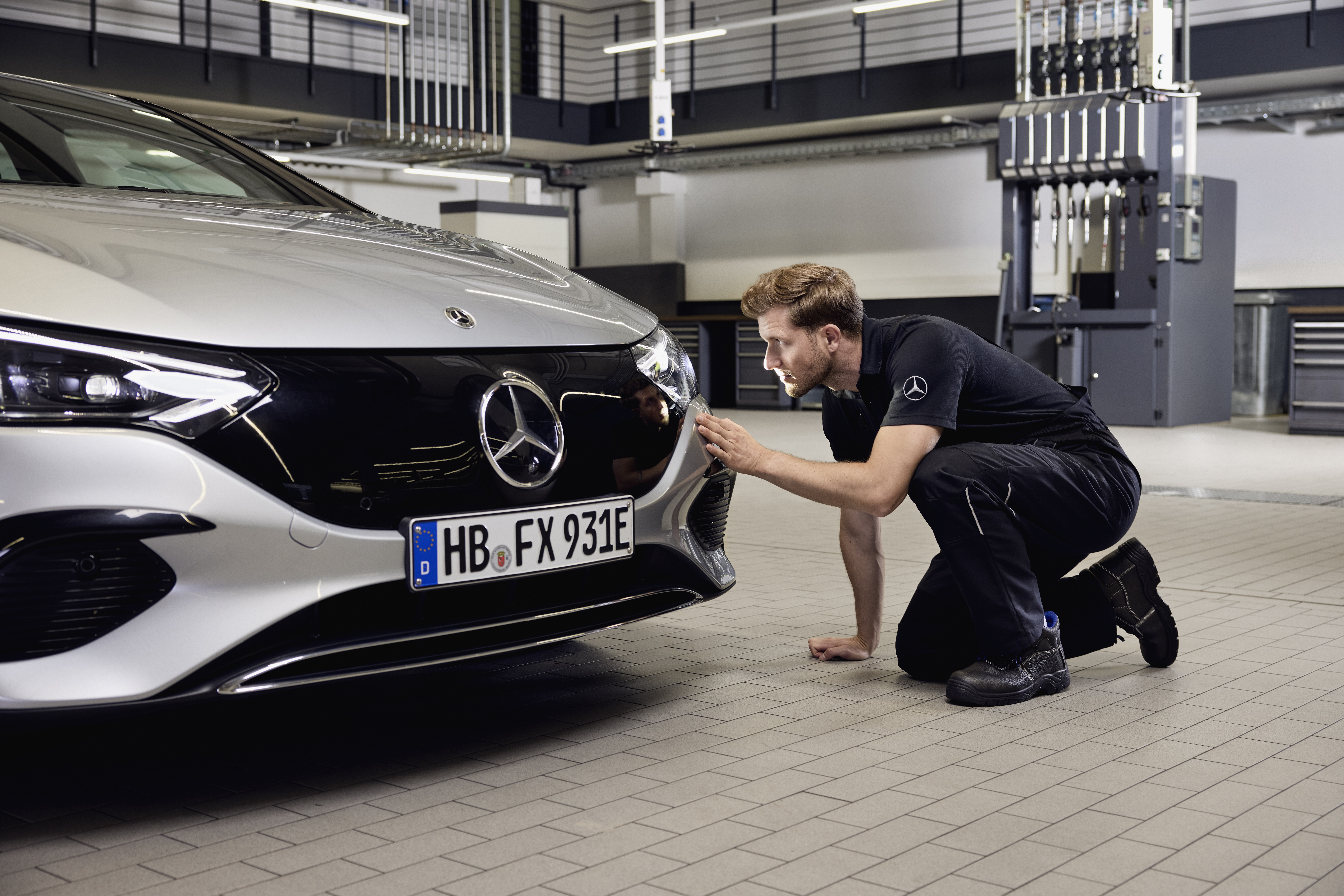 Mercedes-Benz Genuine Headlights Replacement Close‑up of a Mercedes‑Benz vehicle front with a technician performing a detailed examination on the replacement of Mercedes-Benz genuine parts.