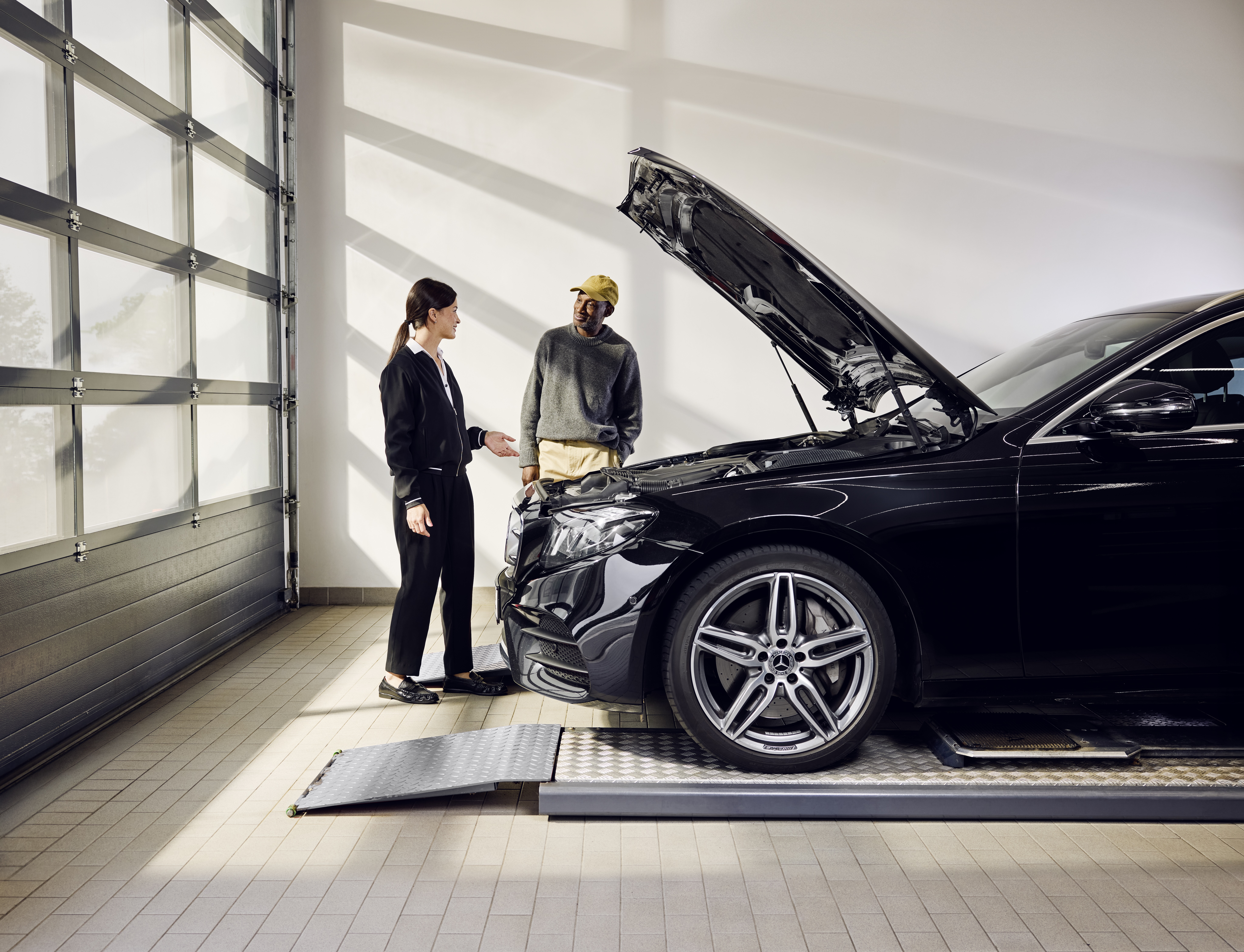 Mercedes-Benz Genuine Parts Replacement Mercedes‑Benz vehicle positioned on a service ramp with the bonnet open during a professional exchange of genuine parts at a service center.