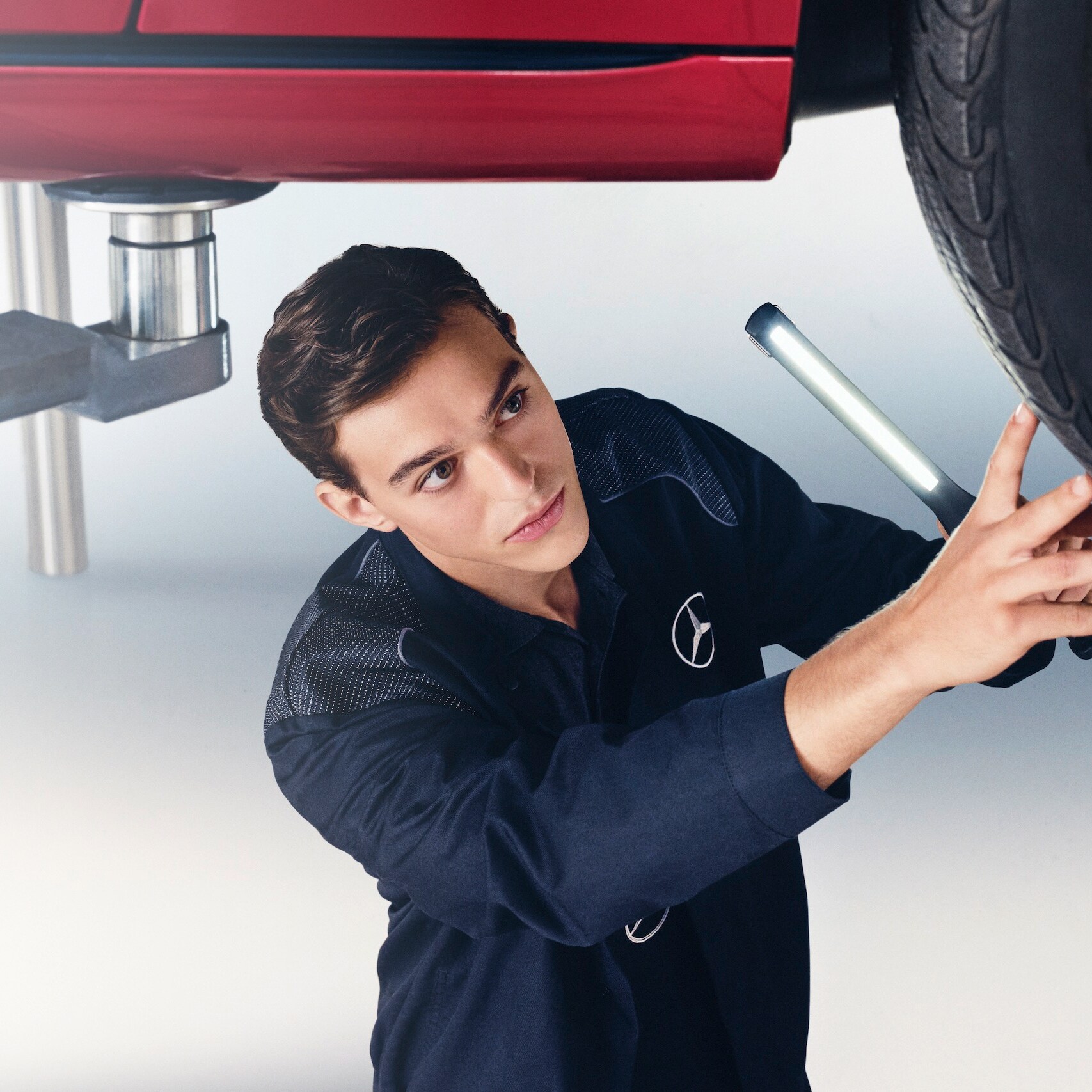 A Mercedes-Benz mechanic examines the wheel of a Mercedes-Benz.