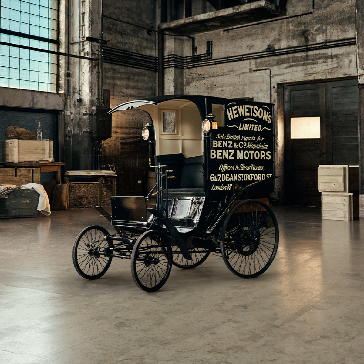 of a a vintage black horse-drawn carriage next to a white Mercedes-Benz van parked indoors