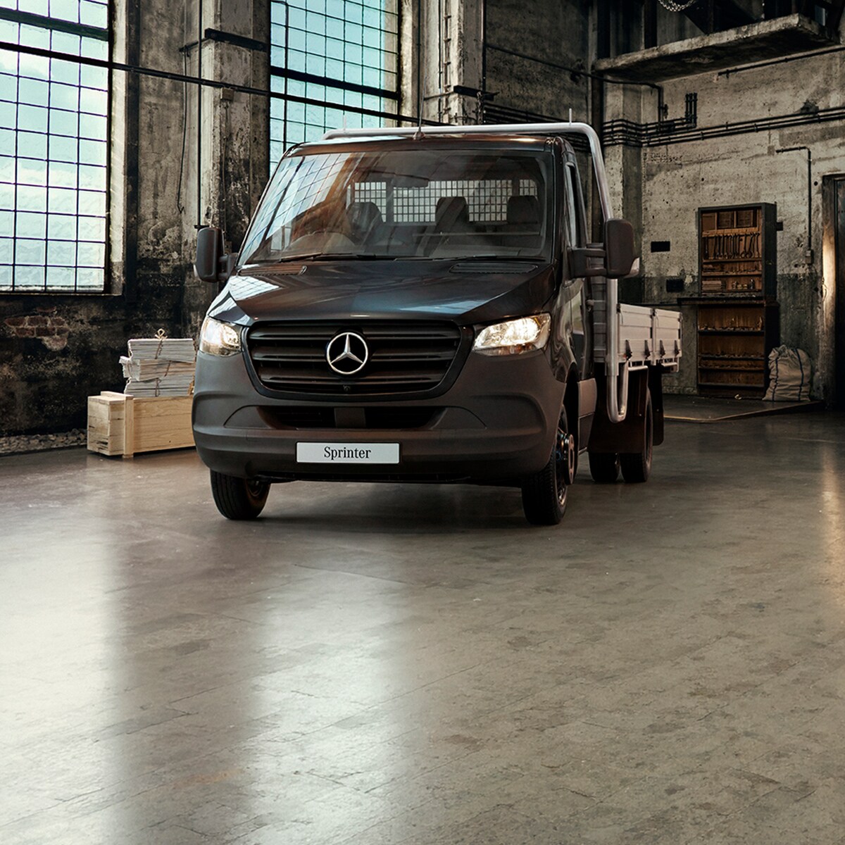 of a a vintage black horse-drawn carriage next to a white Mercedes-Benz van parked indoors