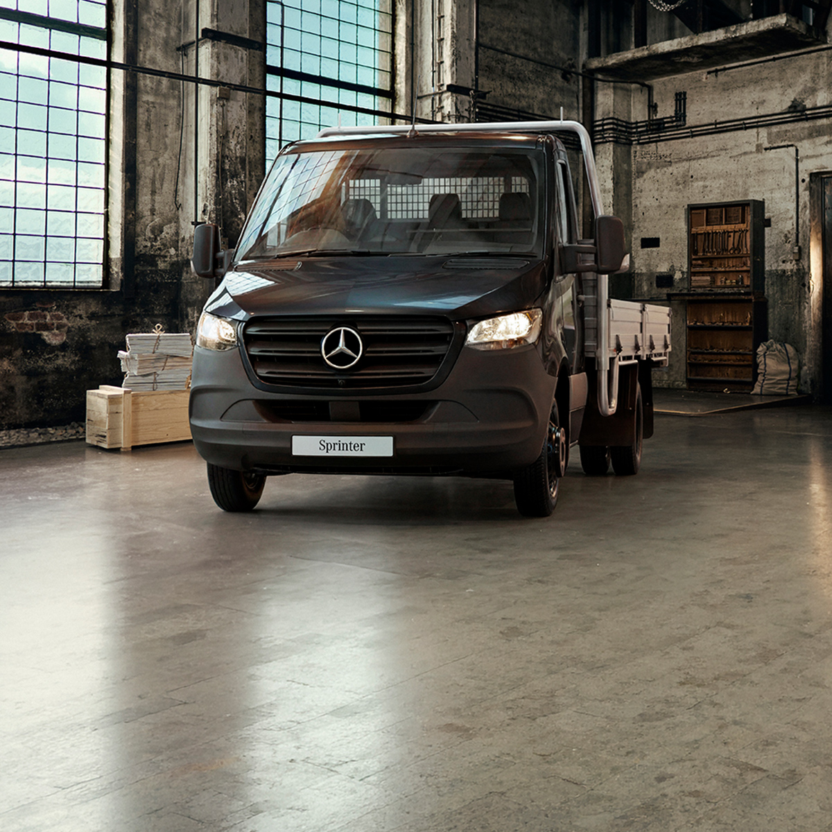 of a a vintage black horse-drawn carriage next to a white Mercedes-Benz van parked indoors