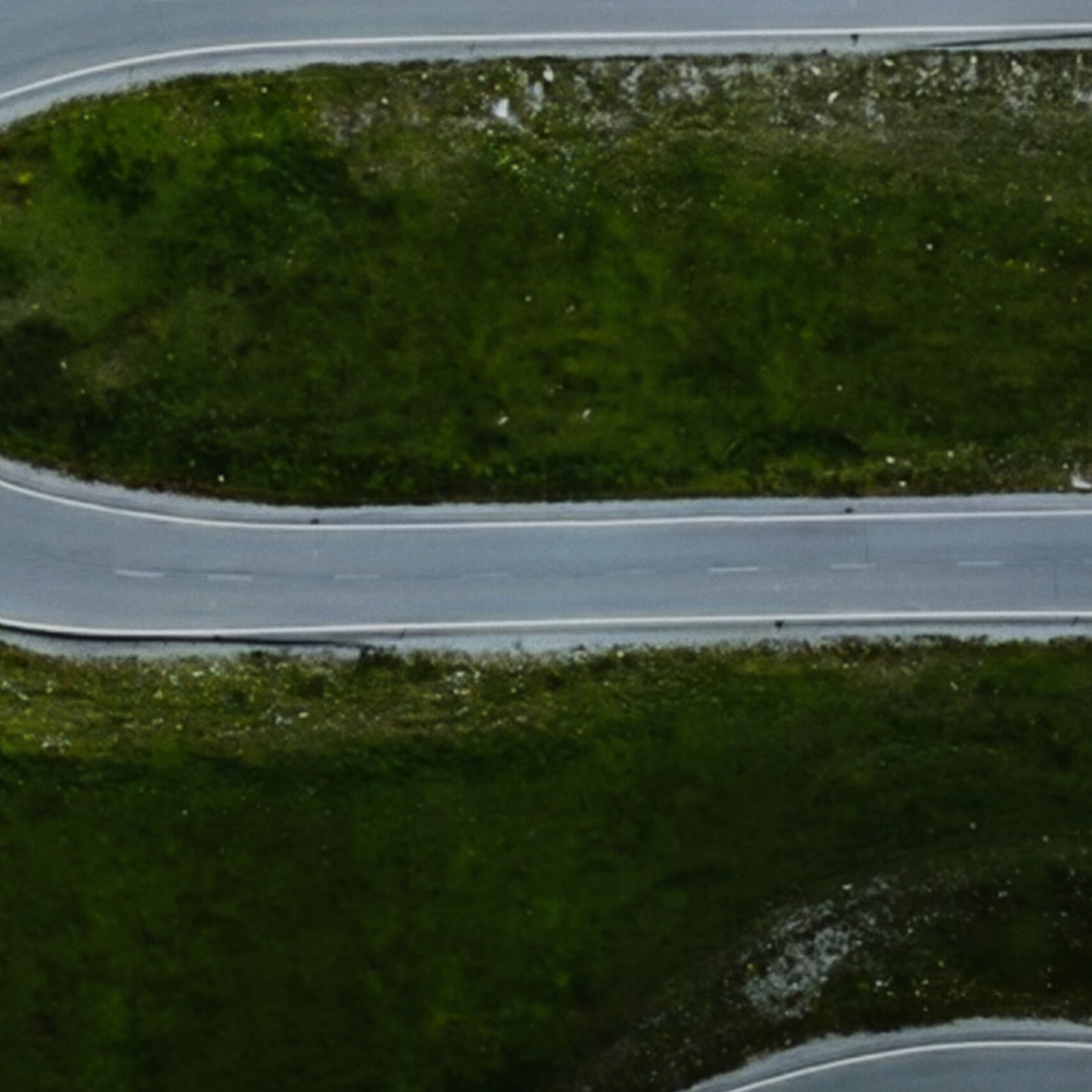 An aerial view of a van driving on a winding road