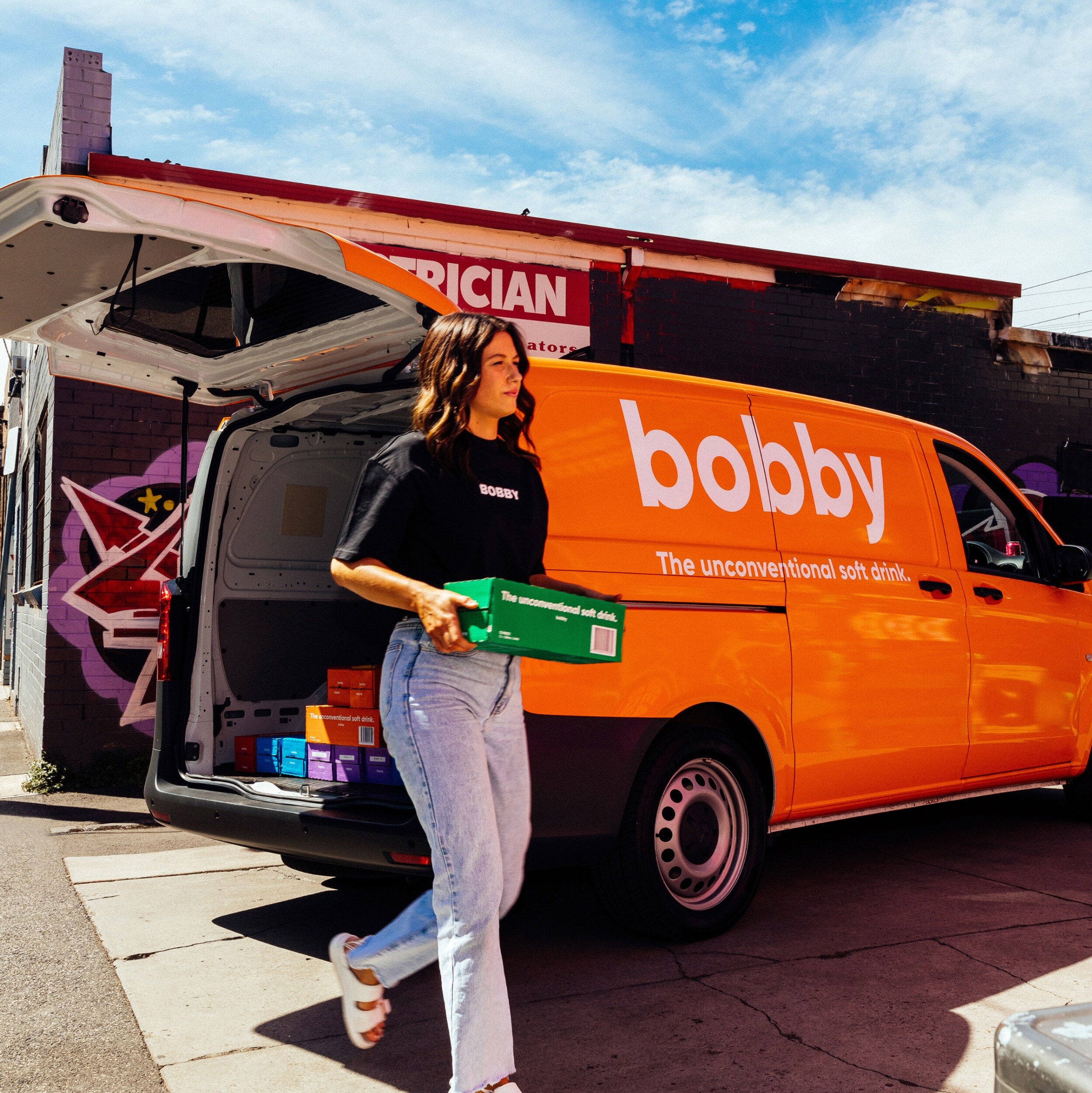 A person carrying  a box of soft drink from an orange van. Image credit/photographer: Sansberry 