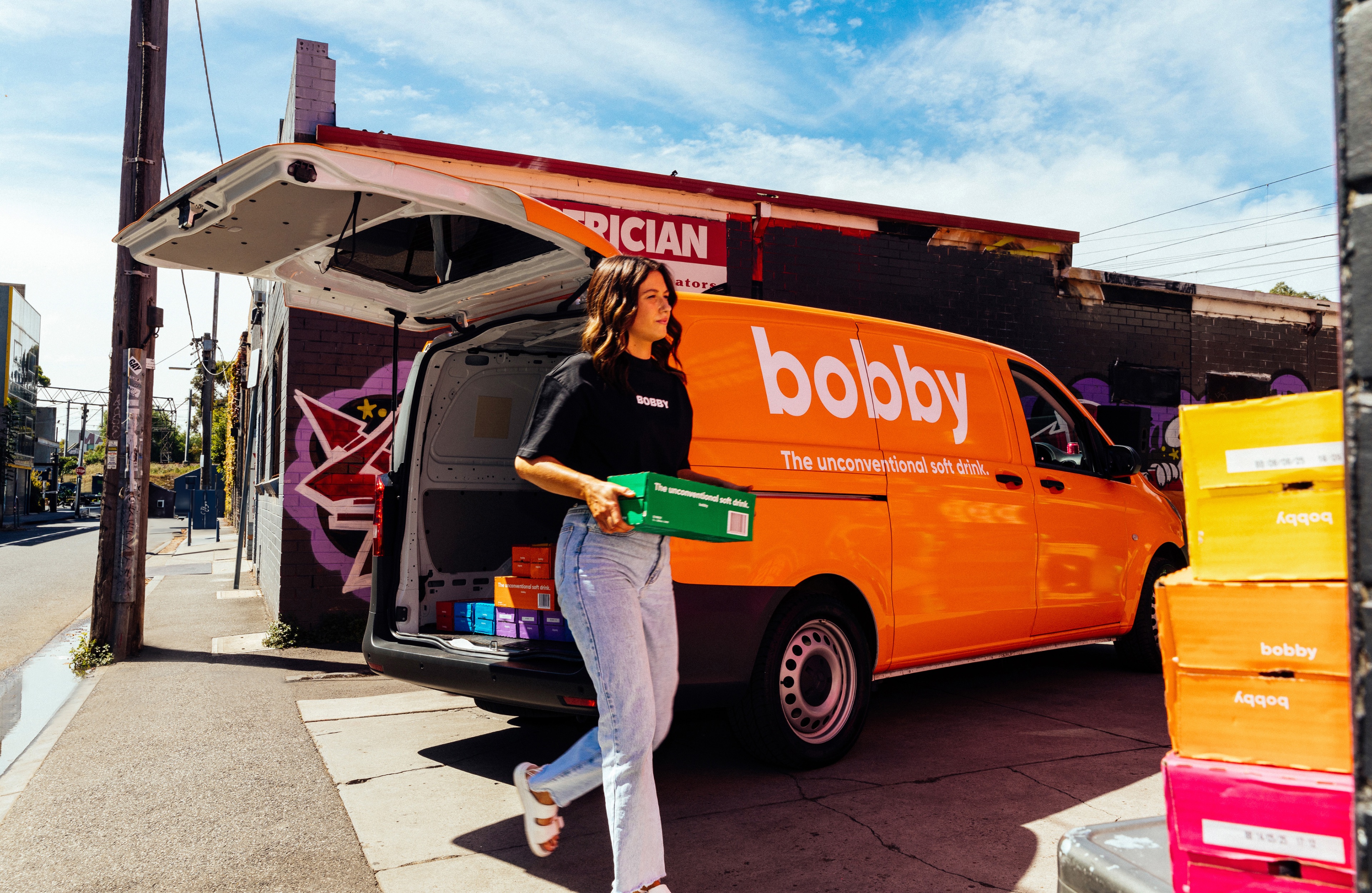 bobby A person carrying a box of soft drink from an orange van. Image credit/photographer: Sansberry