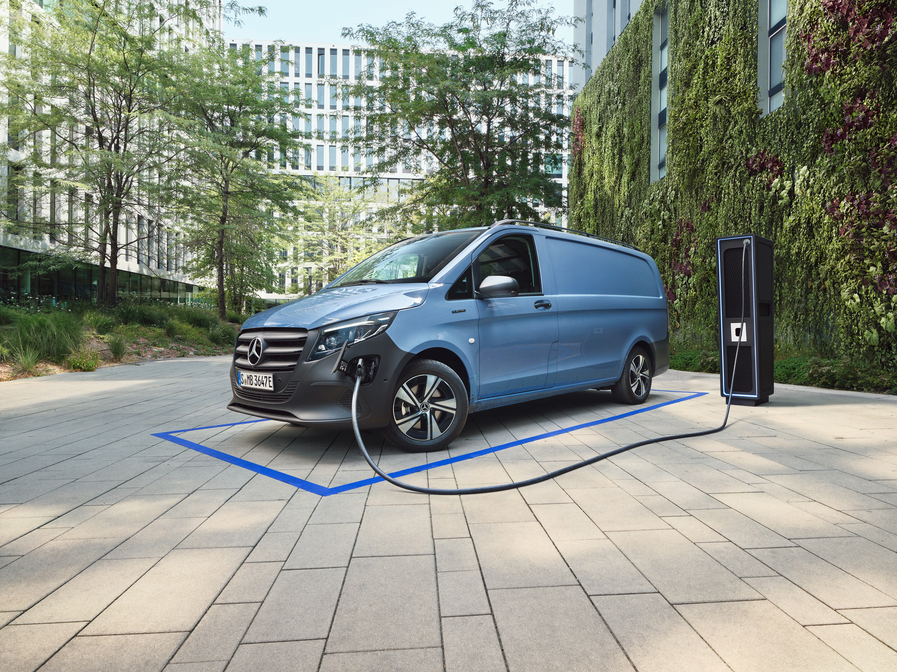 Mercedes-Benz electric van lineup displayed in futuristic warehouse with illuminated charging bars