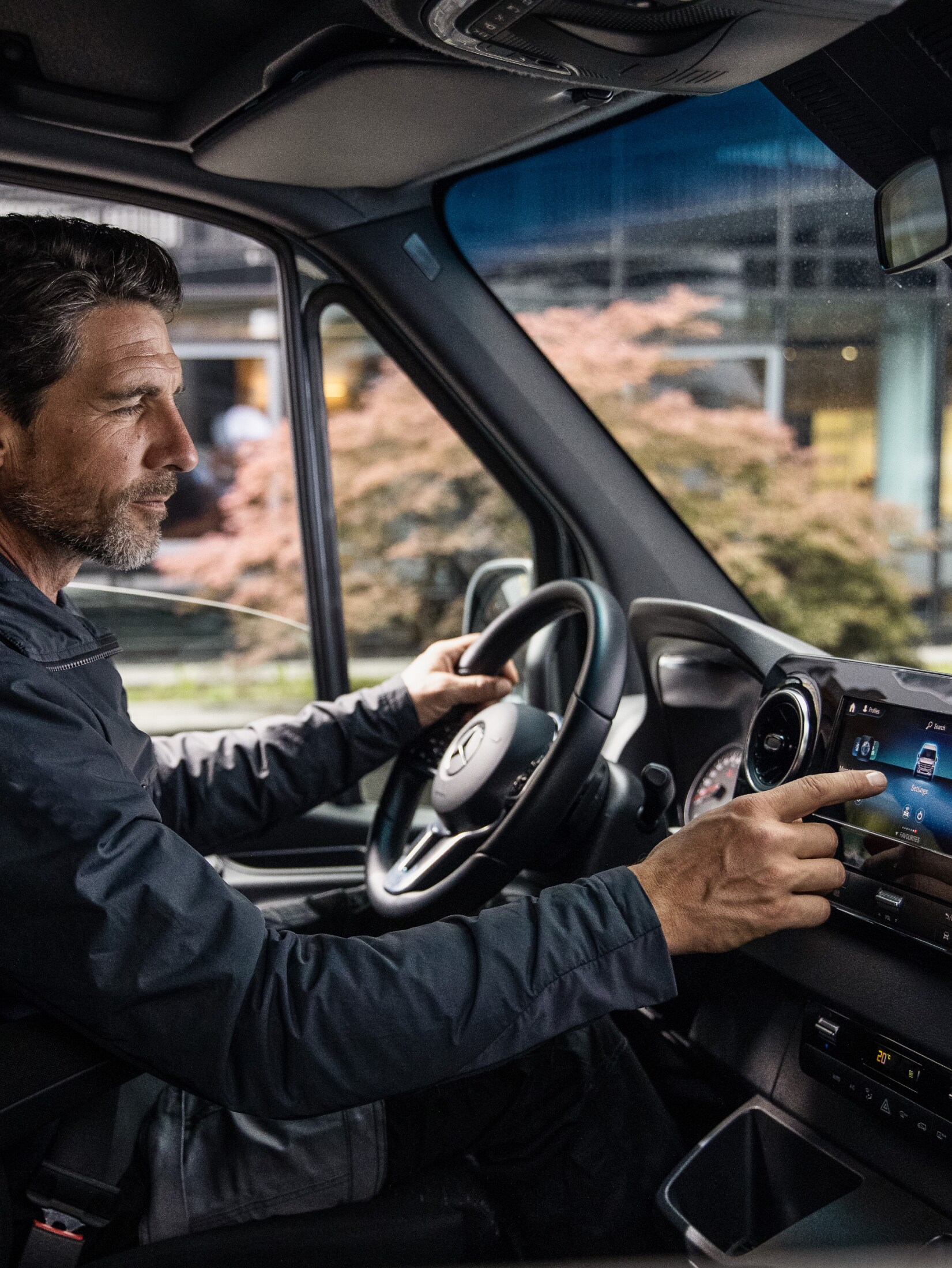 A man tapping on the touchscreen in his van
