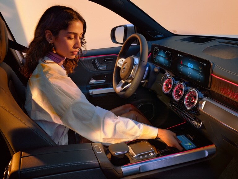 A woman charges her smartphone wirelessly in the oddments tray of her Mercedes-Benz.