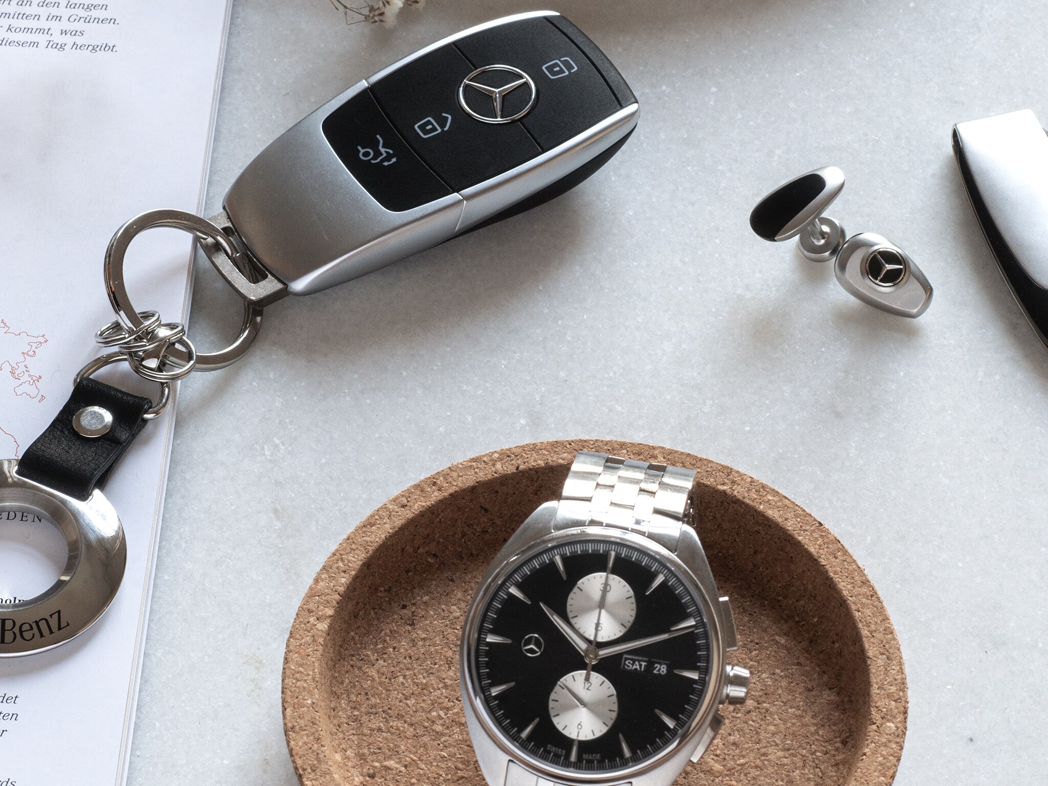 The image shows accessories such as a key ring and a watch from the Mercedes-Benz Collection.