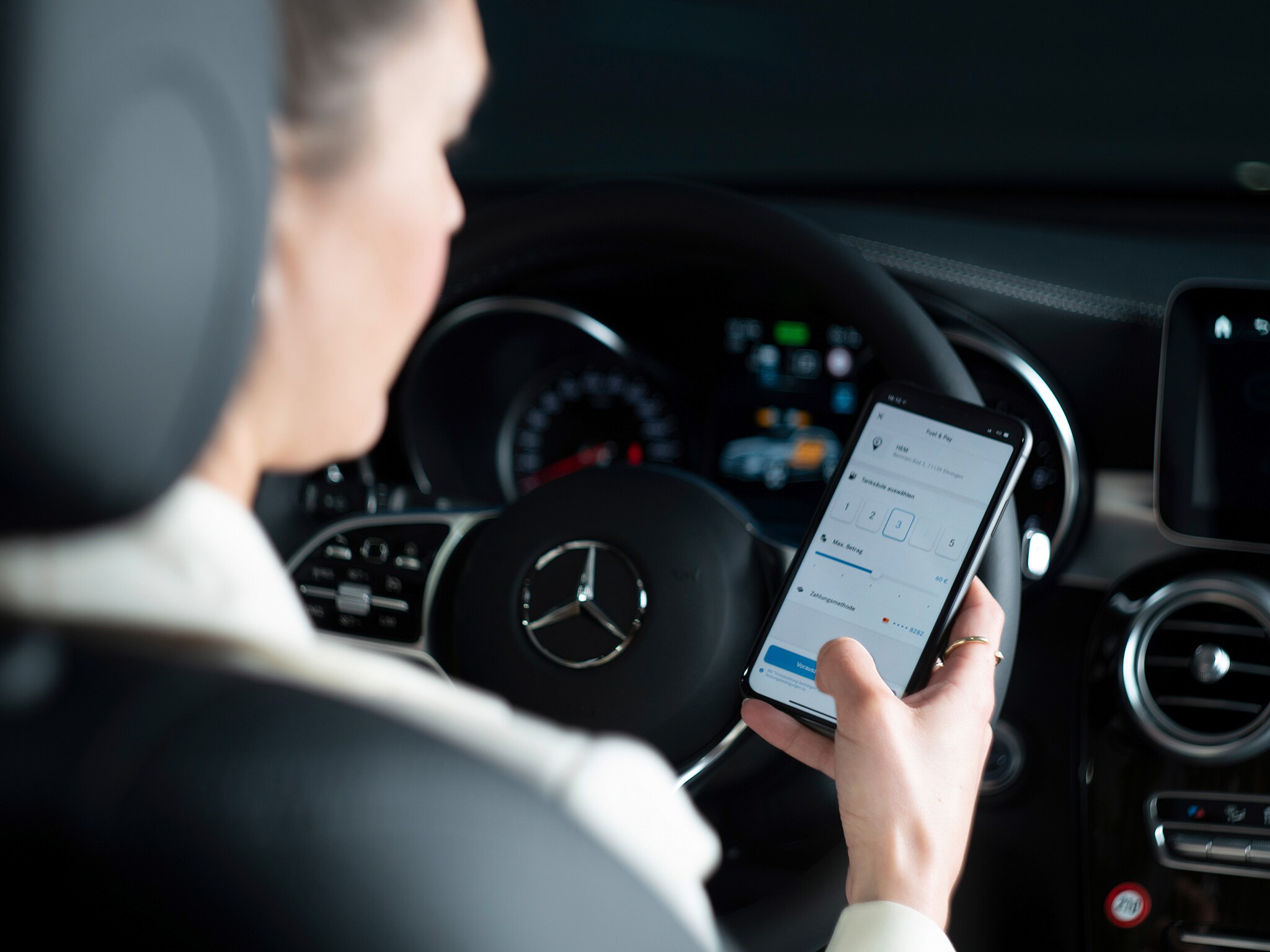 The image shows a woman using the Mercedes-Benz App on her smartphone.