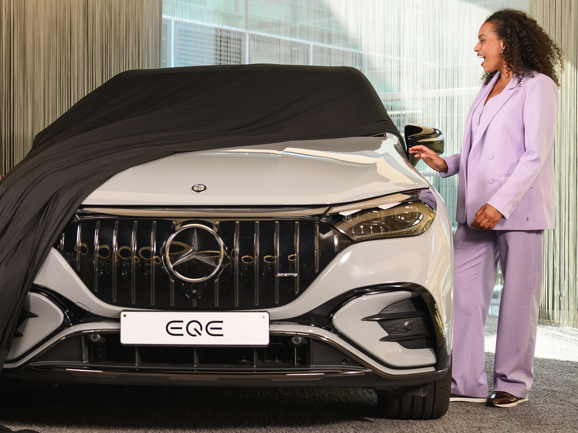 Person unveiling their new car in a Mercedes-Benz showroom.