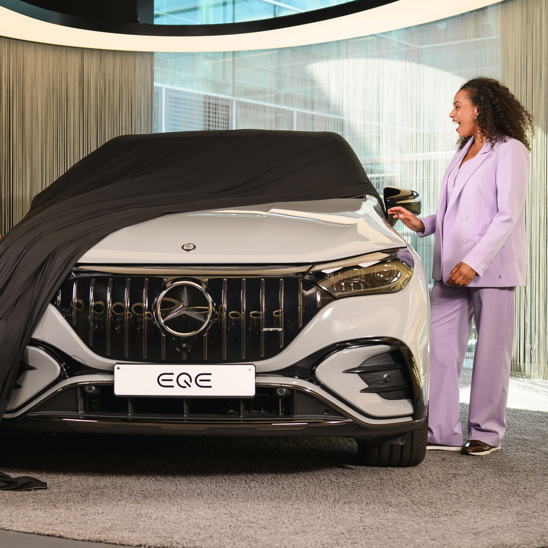 Optimal insurance cover for your Mercedes-Benz Person unveiling their new car in a Mercedes-Benz showroom.